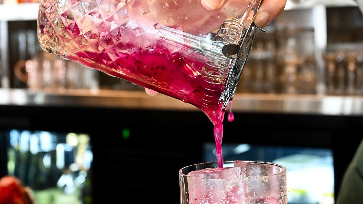 cocktail being poured at bar