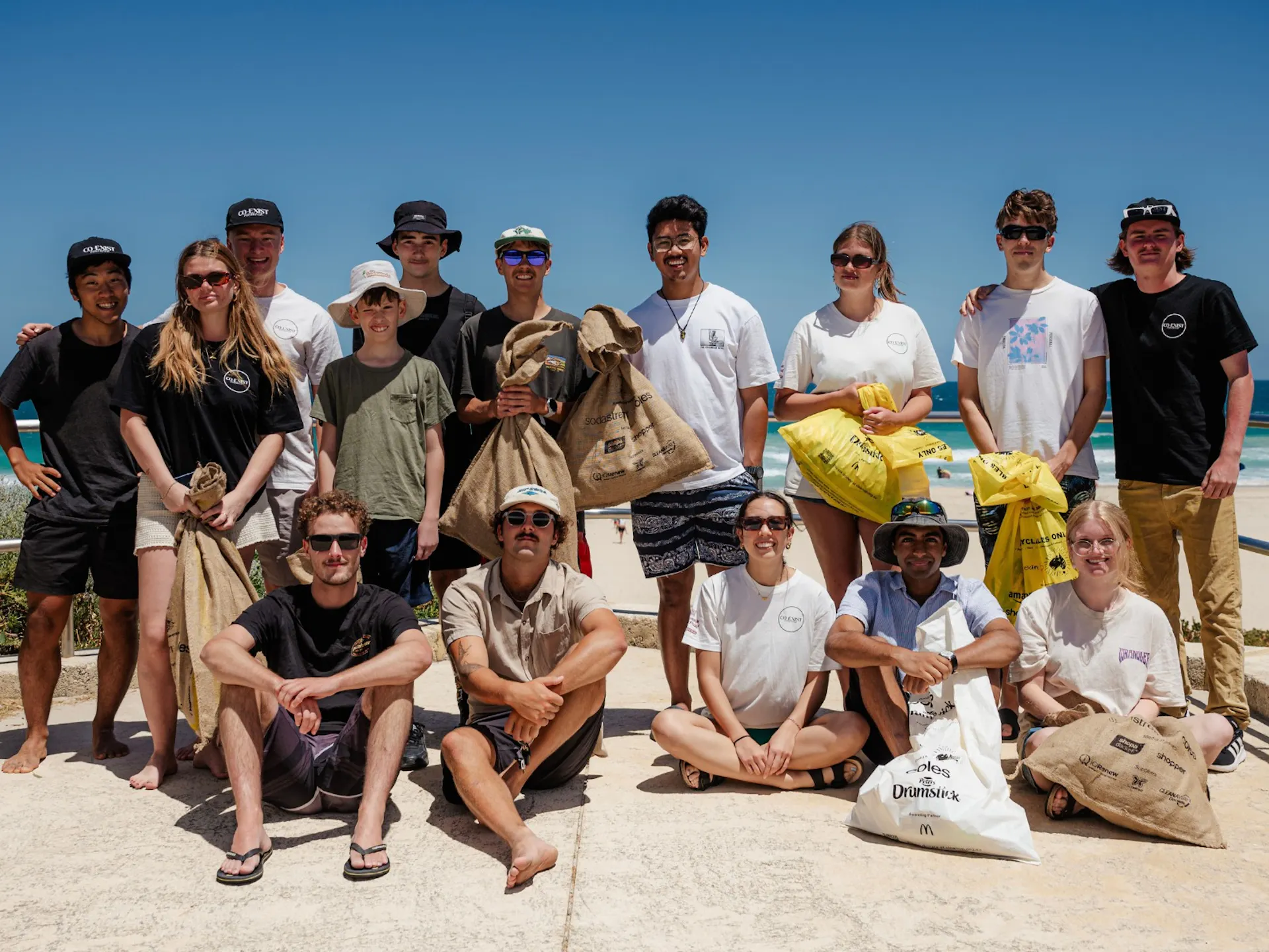 A group of people at the beach, with bags full of rubbish.