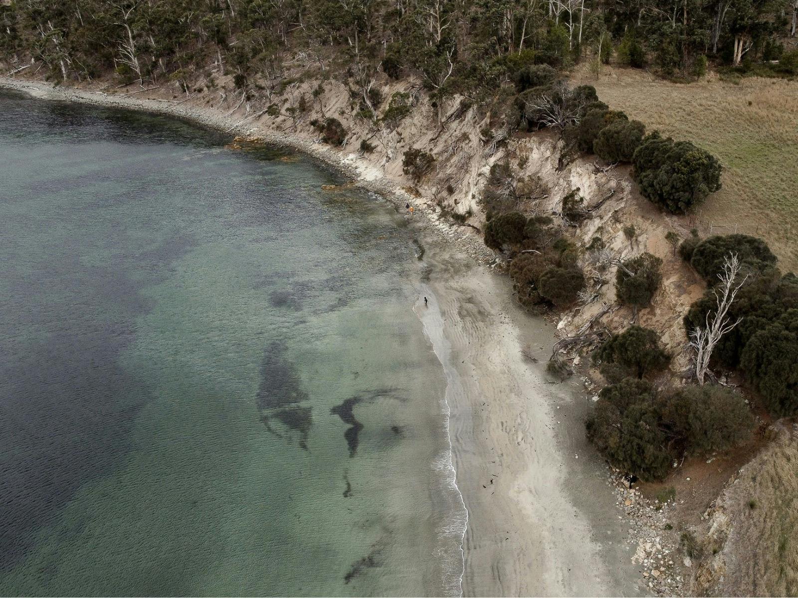 Aerial view of eroded coastal cliffs meeting clear turquoise water.
