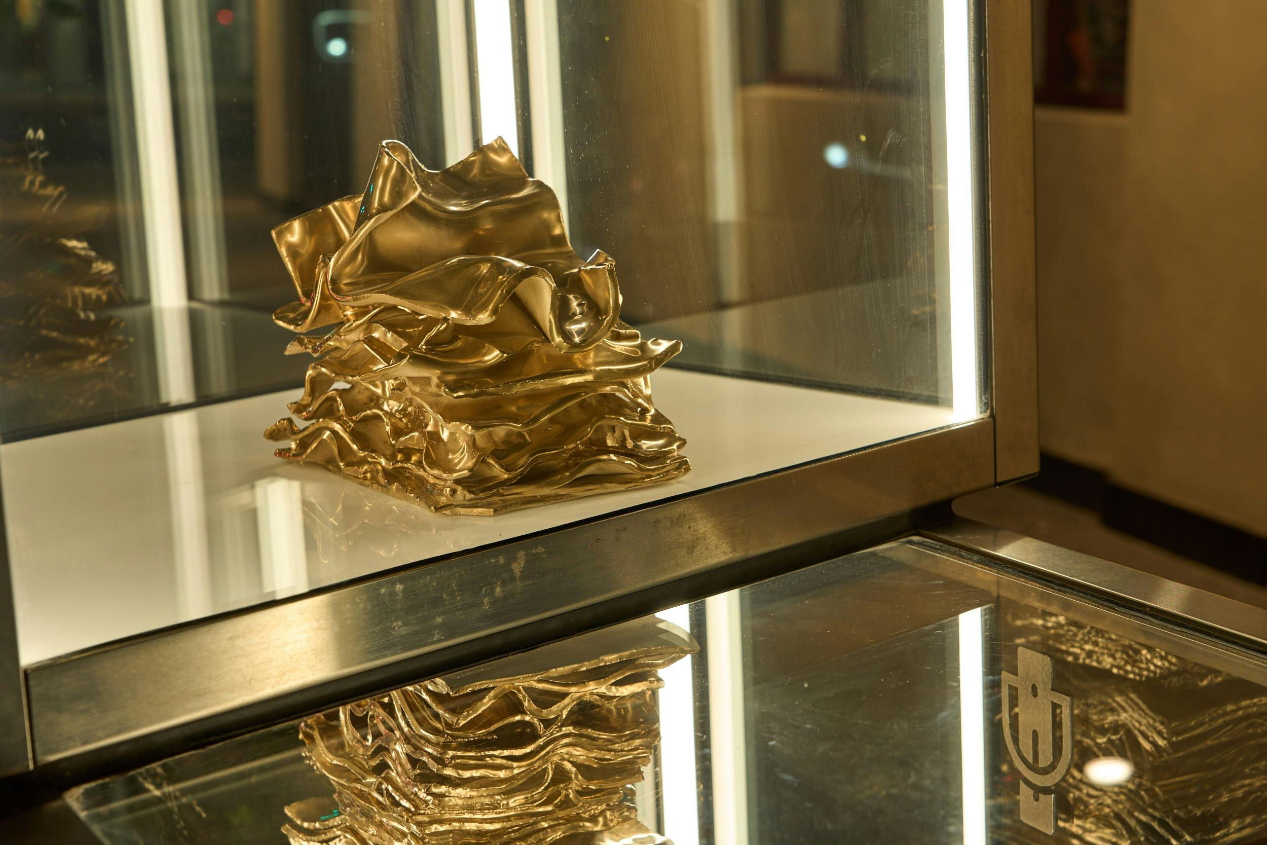 Close up of golden ceramic stack of cash in a clear perspex box taken at night.