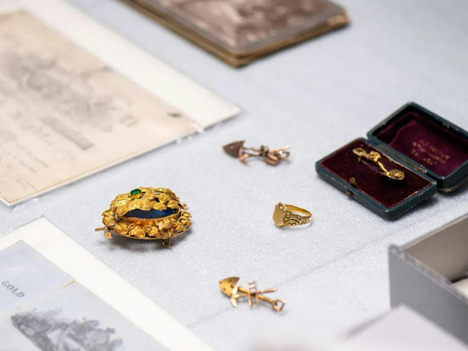 Collection of 19th century gold jewellery (pins and brooch) surrounded by documents