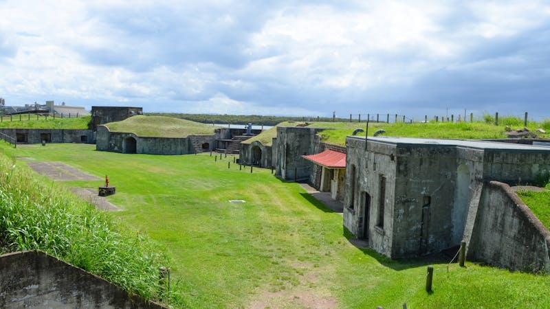 Fort Lytton buildings with grassy surrounds and cloudy sky.