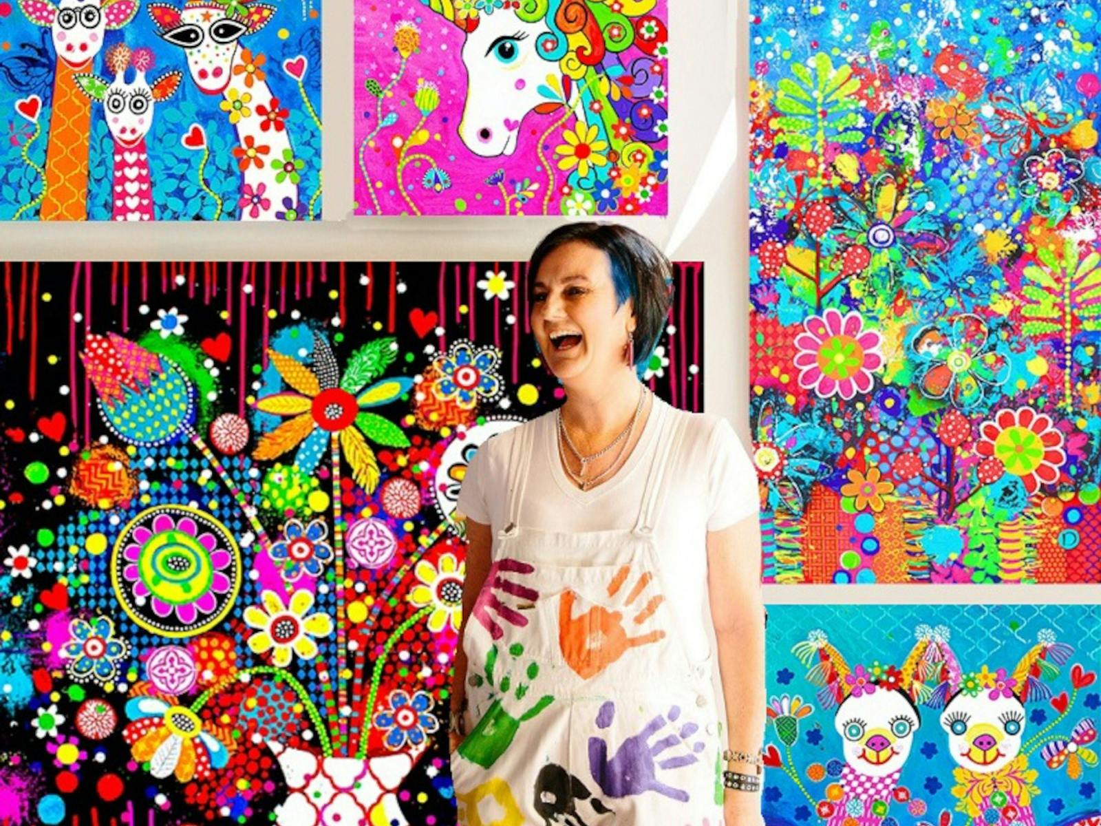 Donna Sharam standing and laughing in front of her very bright artworks