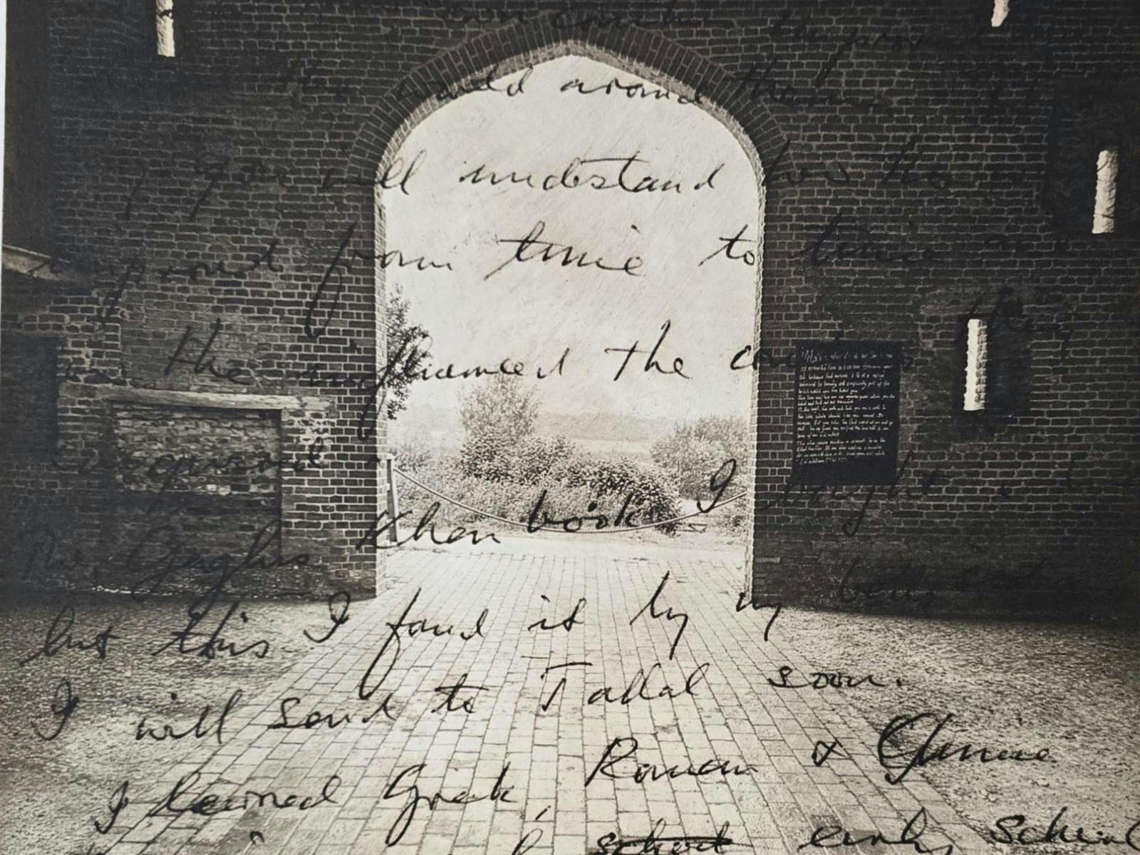 A black and white photograph of an arch with cursive text written over it