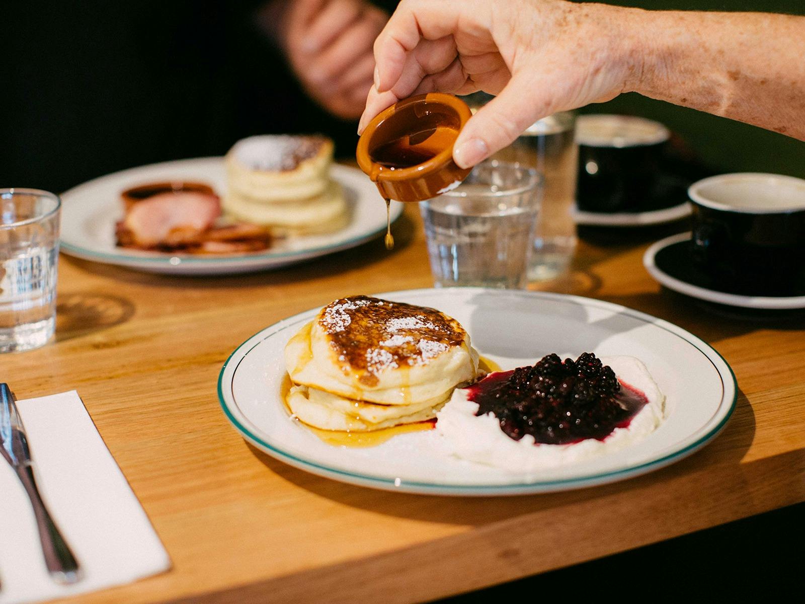 Hotcakes with whipped mascarpone , fruit compote and maple syrup (hotcakes with bacon in background)