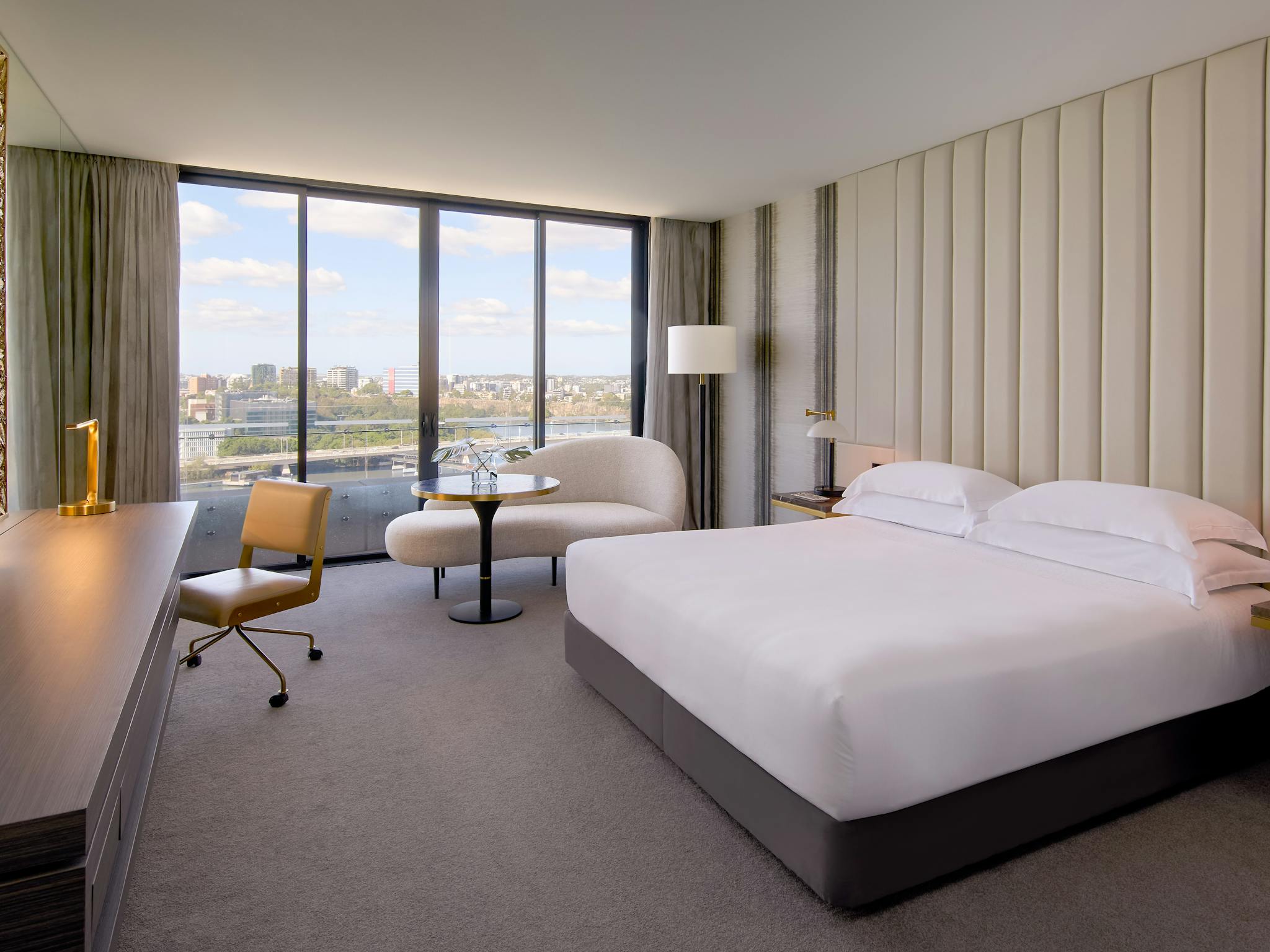 Luxury hotel room with king bed, lounge seating and floor-to-ceiling views across Brisbane Luxury hotel room with king bed, lounge seating and floor-to-ceiling views across Brisbane