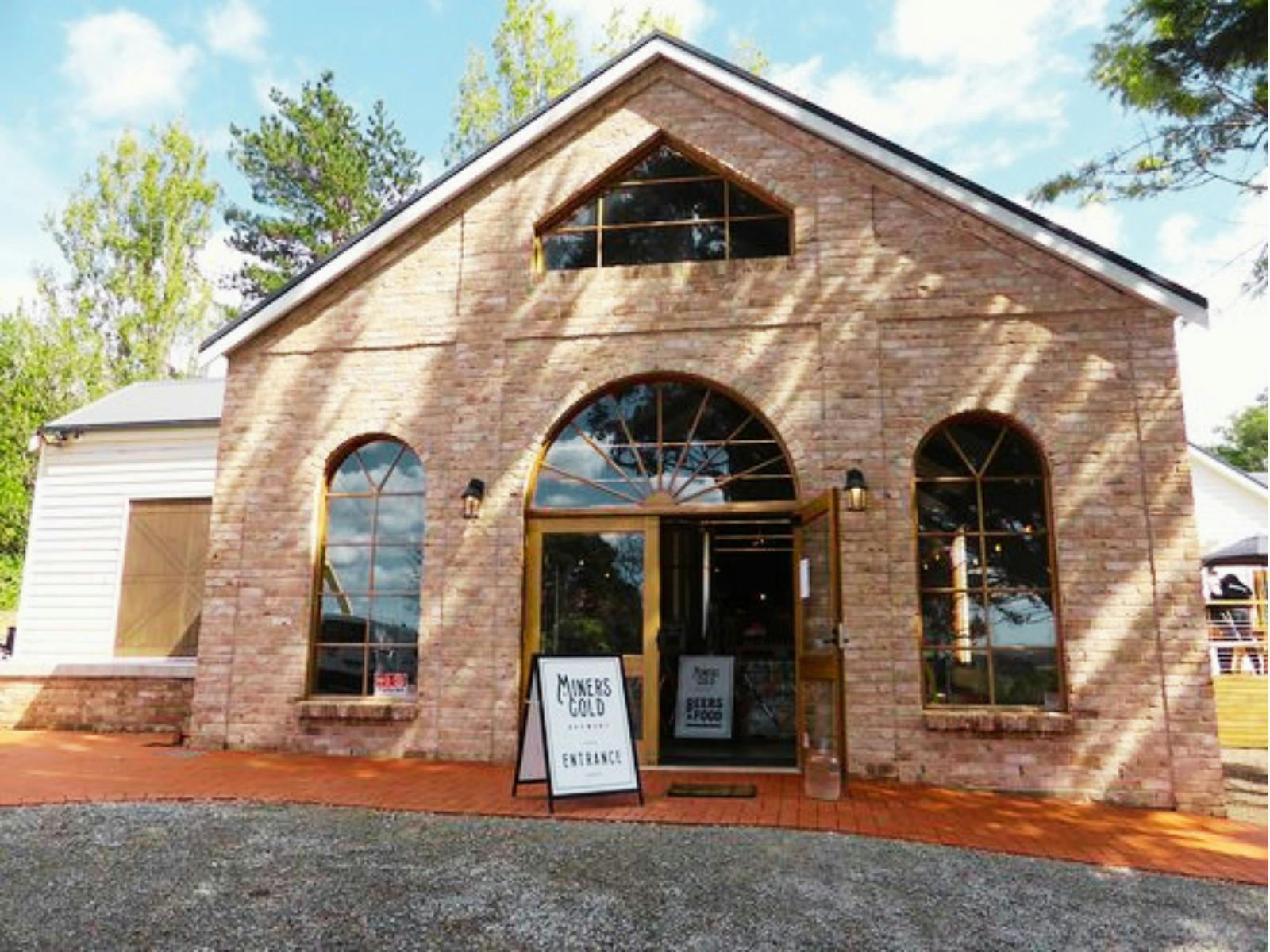 Exterior of restored brick brewery building with arched windows and entrance signage.