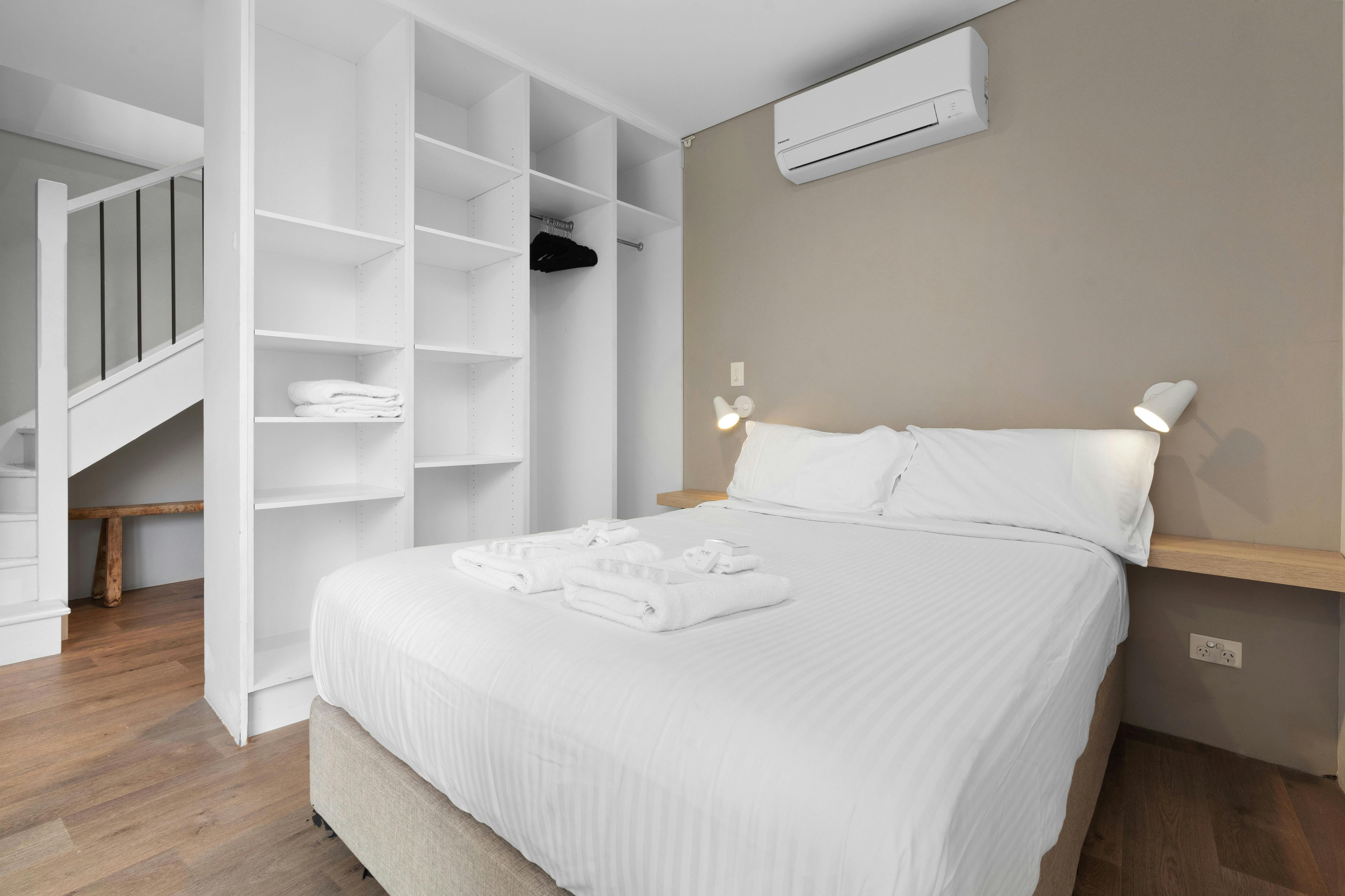 舒適的臥室配有兩張床、大衣櫃和柔和的燈光。