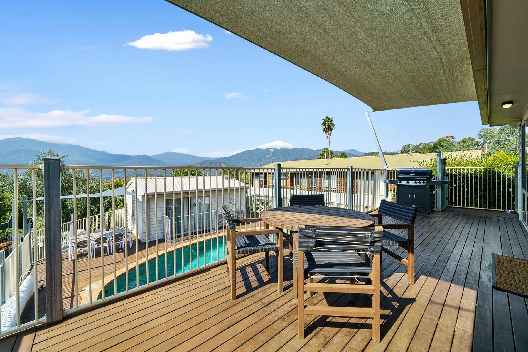 Balcony shot overlooking an outdoor swimming pool and mountains in the background