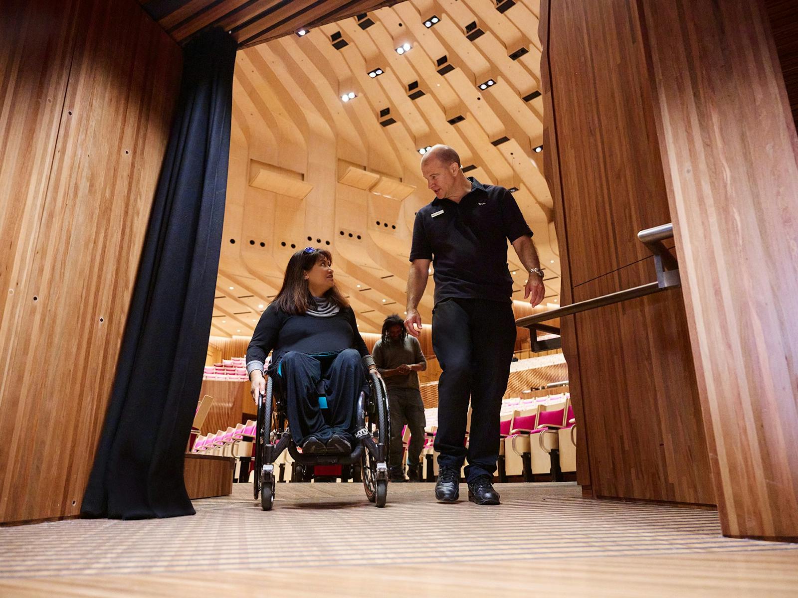 車椅子の女性と、その隣に立つ男性のツアーガイド