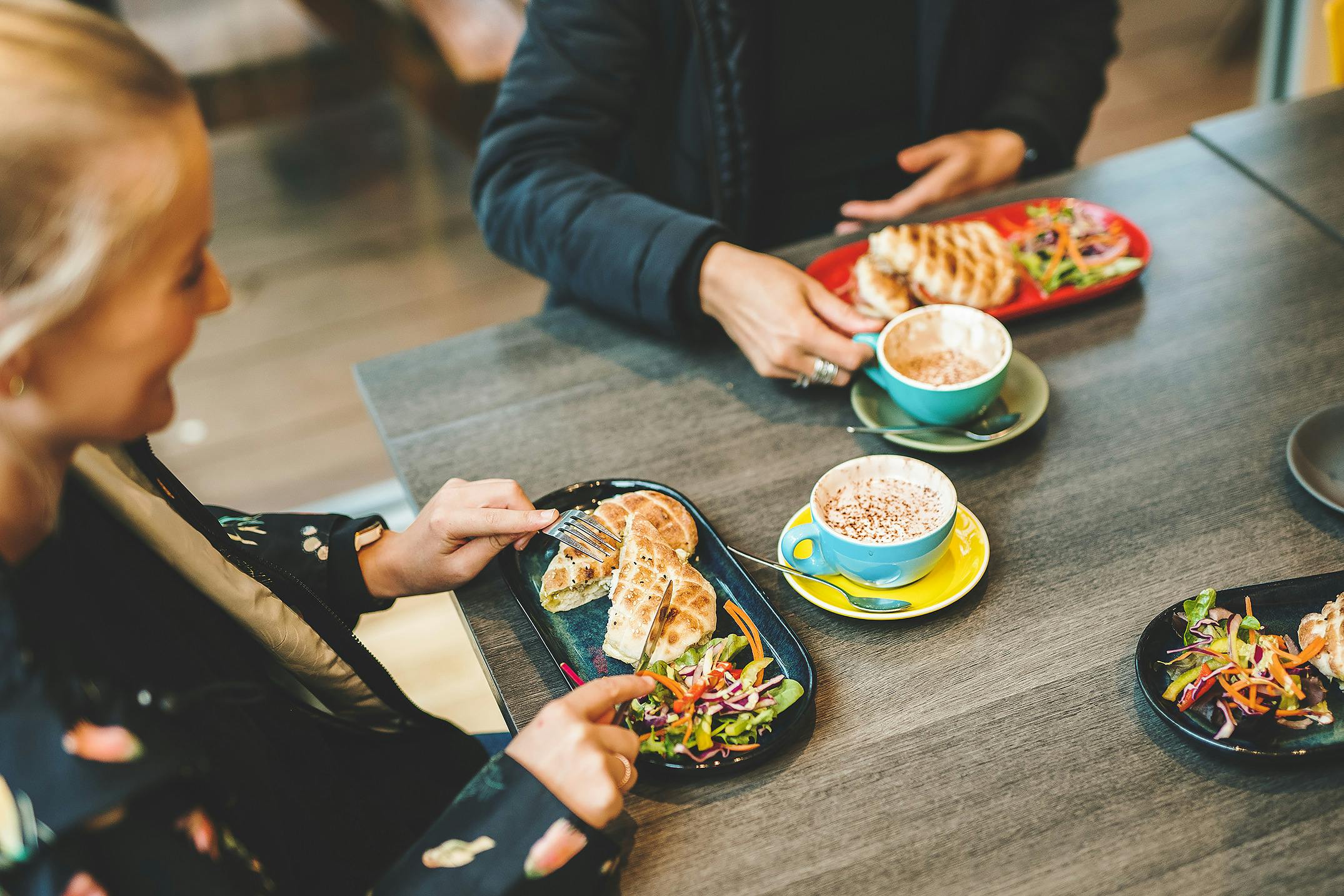 Looking down at table of people eating pitas and drinking coffee