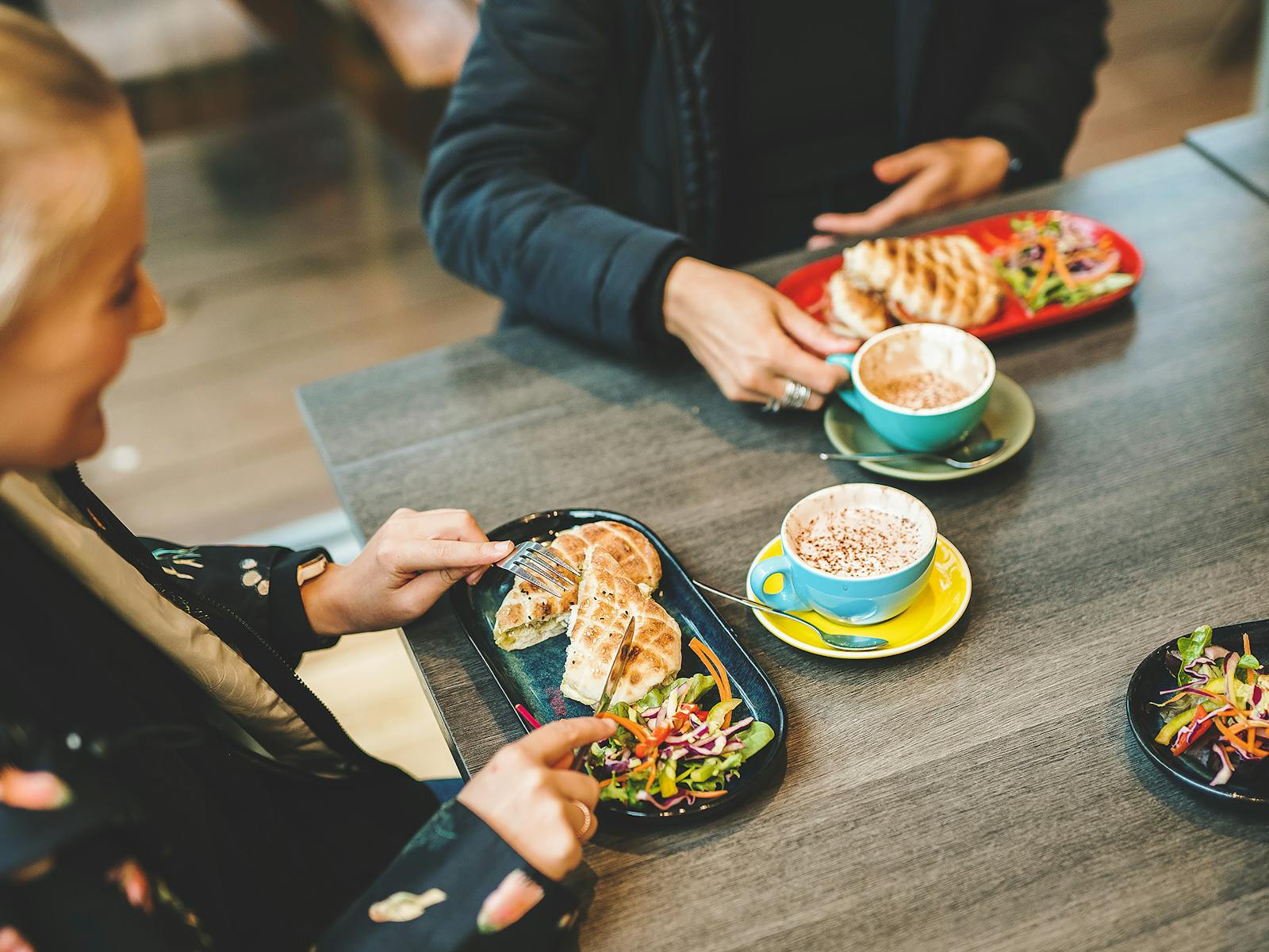 Looking down at table of people eating pitas and drinking coffee