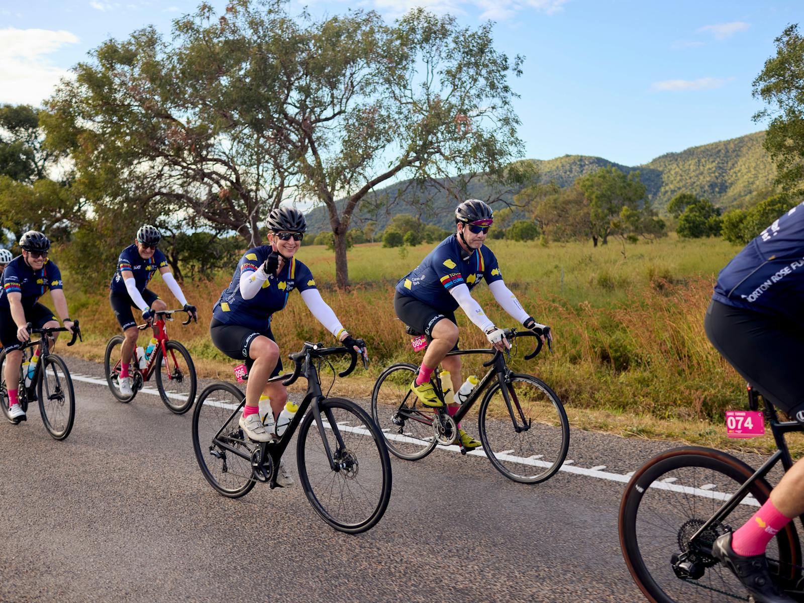 Cyclists riding on the road in a peloton with grass and hills scenic background
