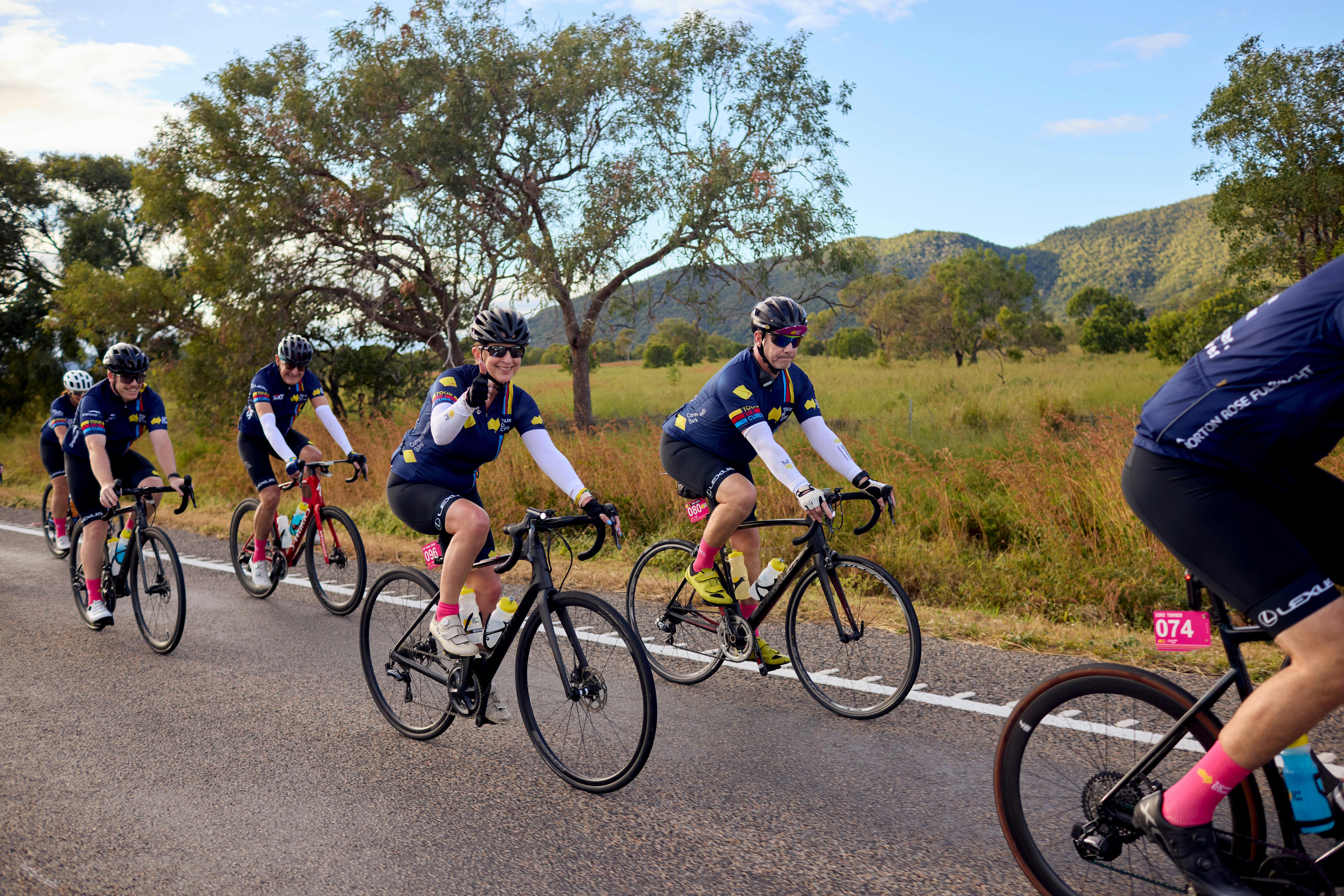 Cyclists riding on the road in a peloton with grass and hills scenic background