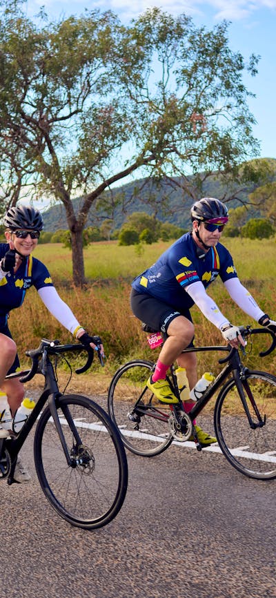 Cyclists riding on the road in a peloton with grass and hills scenic background