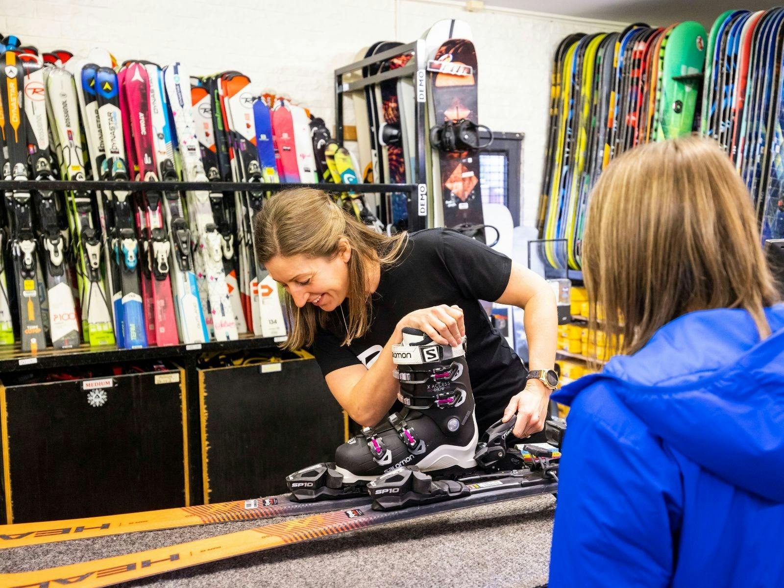 Staff member setting up ski's at Ray's Ski Hire with Guest