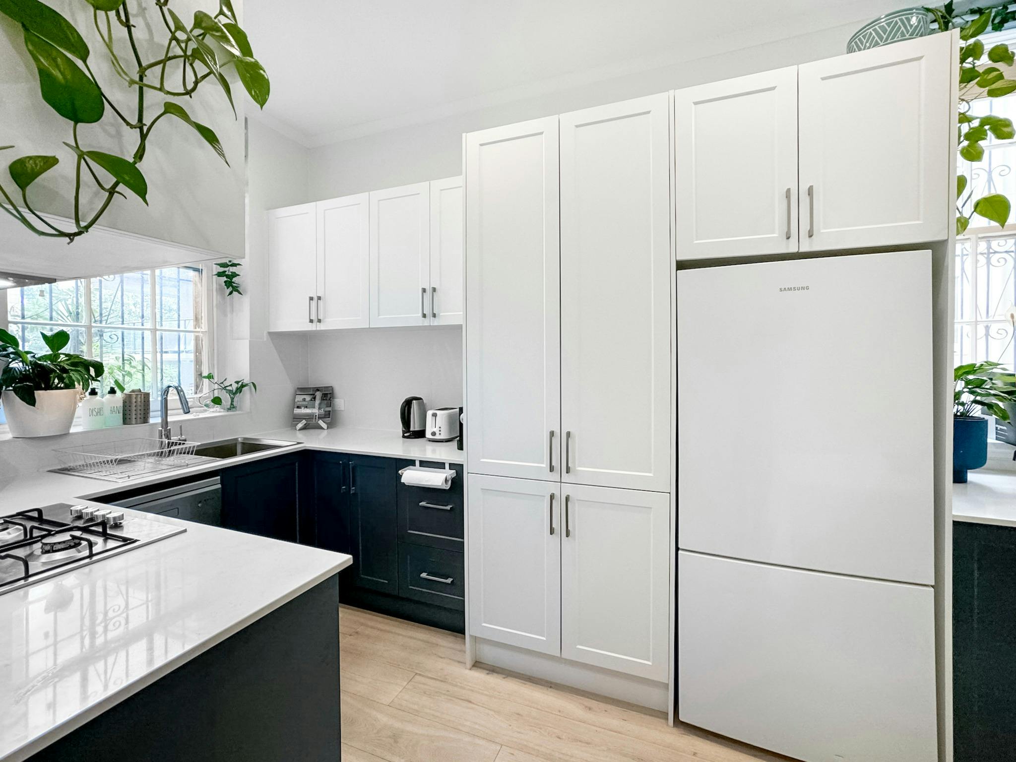 廚房配有乾淨的白色櫥櫃、現代化的電器和豐富的植物裝飾。