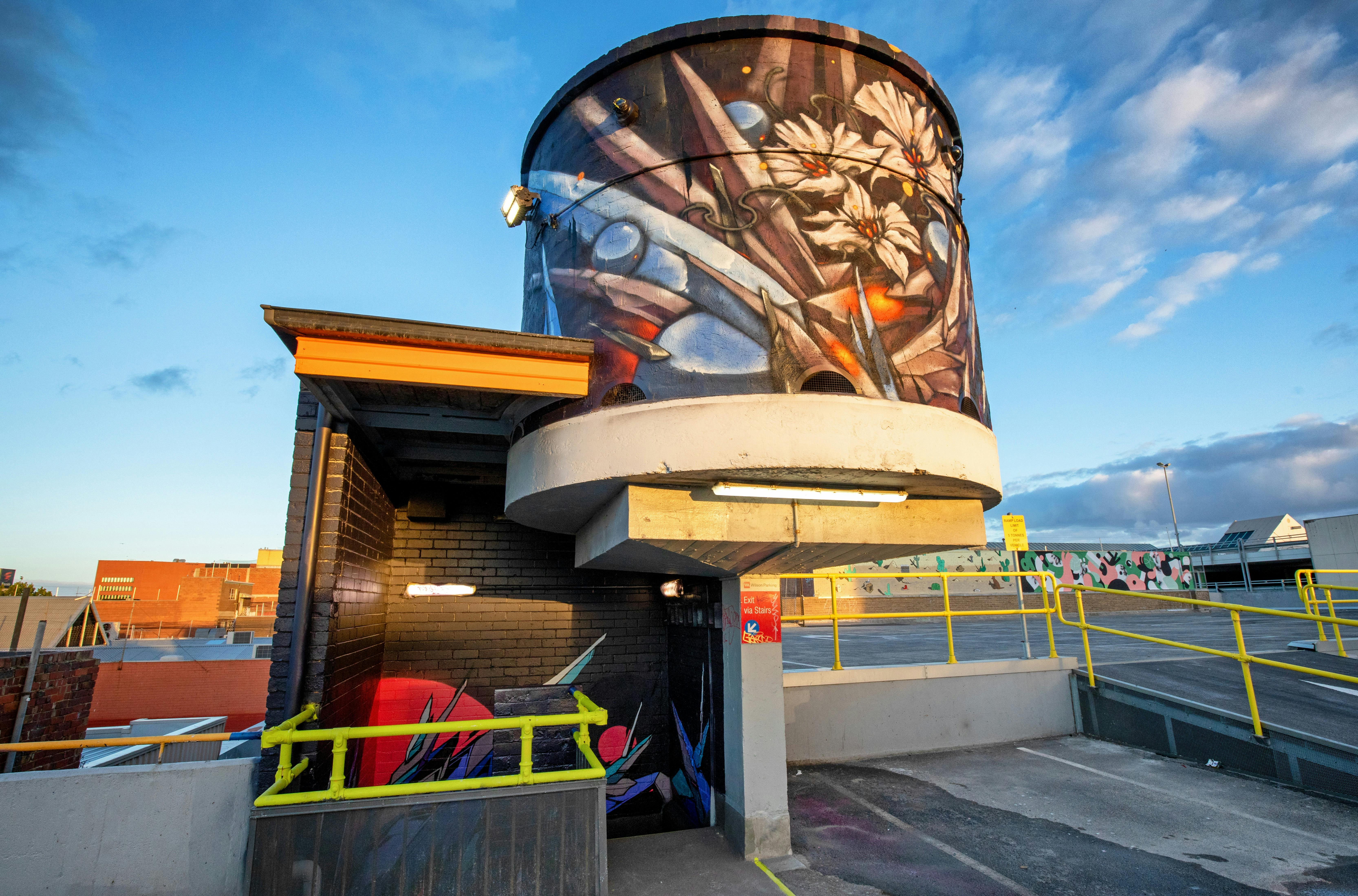 A painted tower atop of a staircase. It has white flowers, blue spikes and silver spheres.