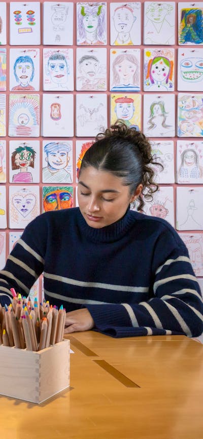 Three young girls sit together at a table, colouring in templates to create their own mini trains