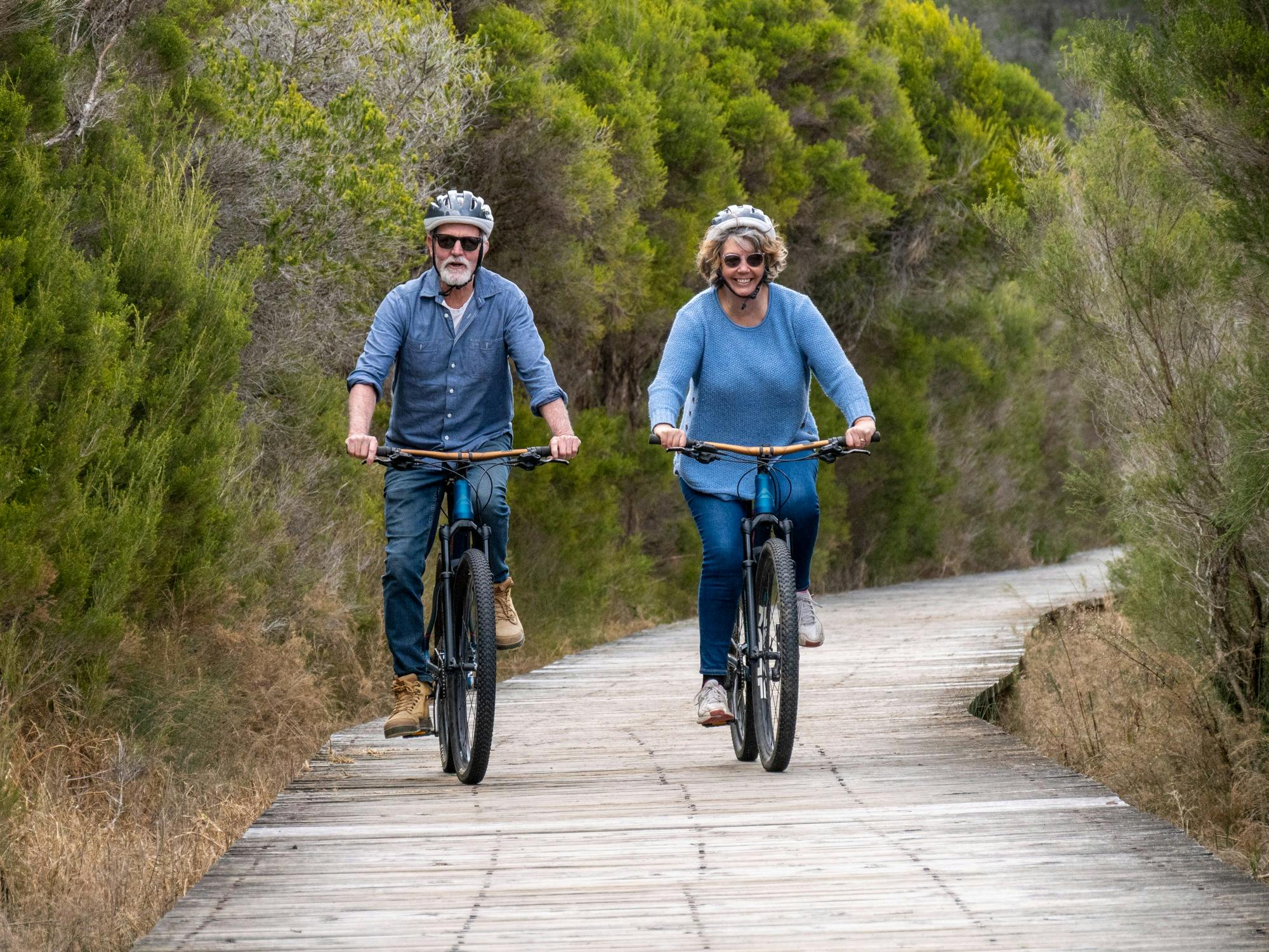 Two guests cycling along the lake boardwalk