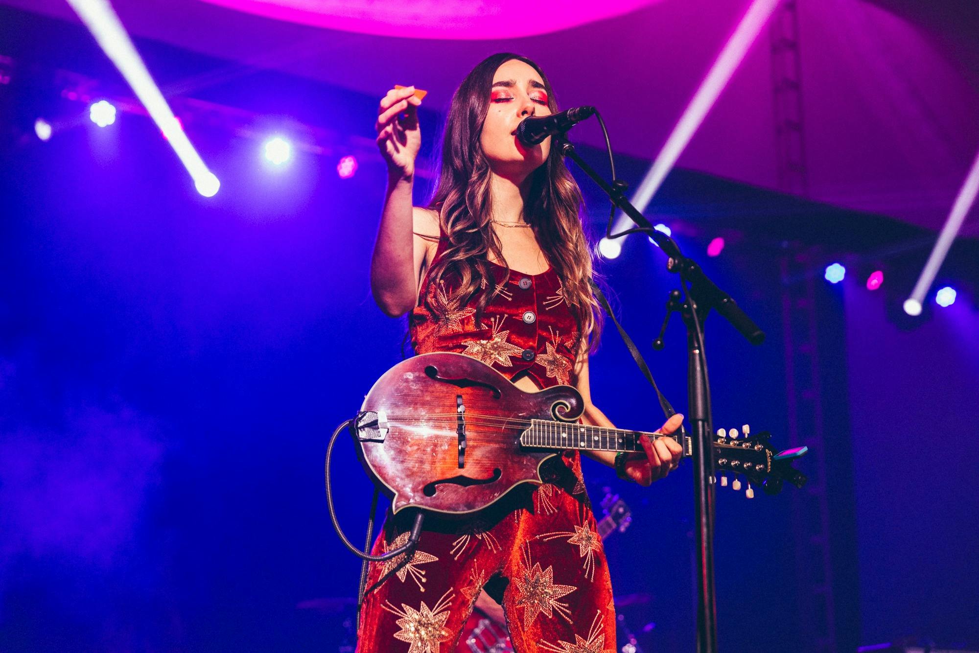 Little Quirks band member standing at microphone with her instrument performing on stage