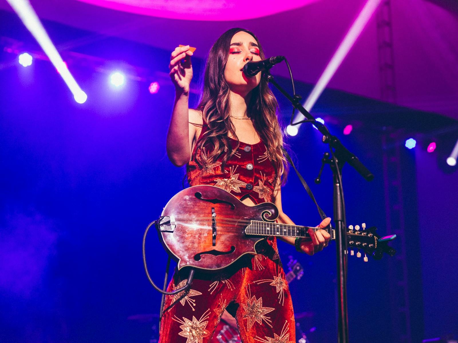 Little Quirks band member standing at microphone with her instrument performing on stage