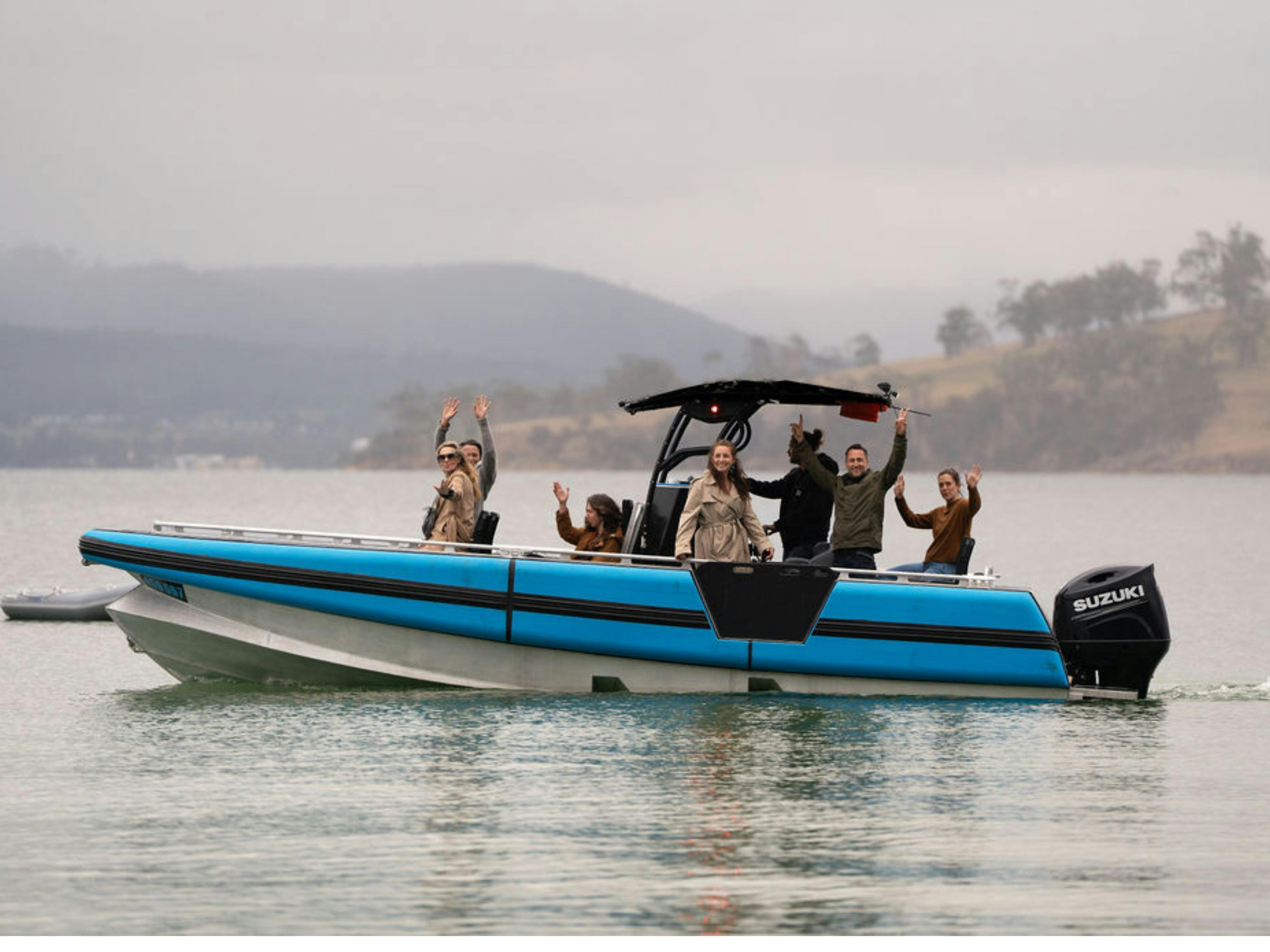 Group of guests waving from Islander's blue vessel on the channel.