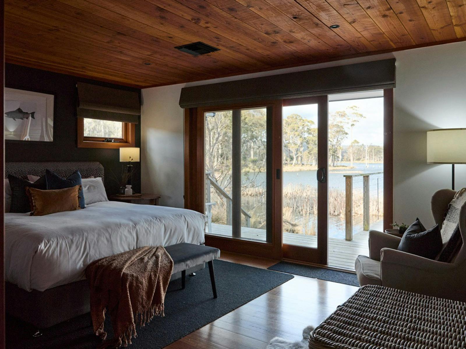 A interior of an accommodation bedroom with deck access overlooking a lake.