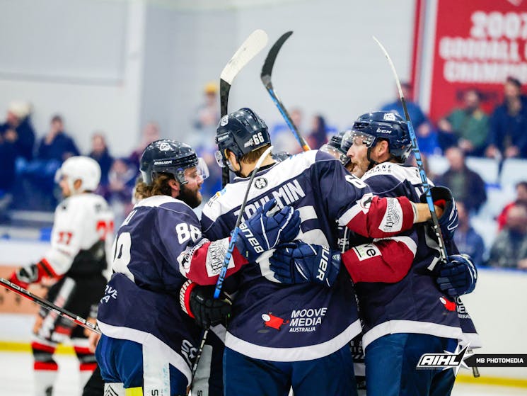 Hockey players hug each other in celebration after a goal