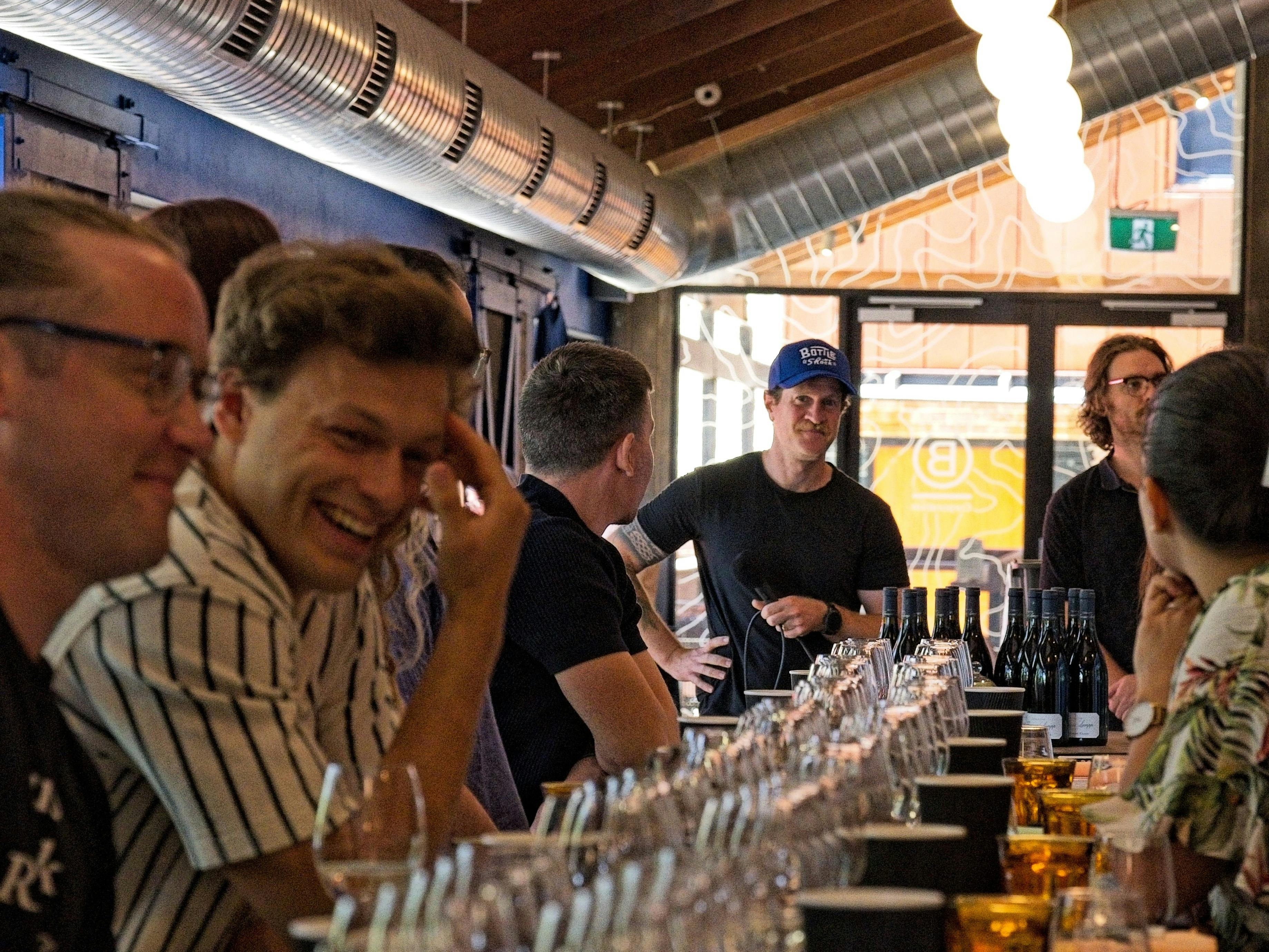 A person in the foreground laughs as answers to a blind tasting round are revealed