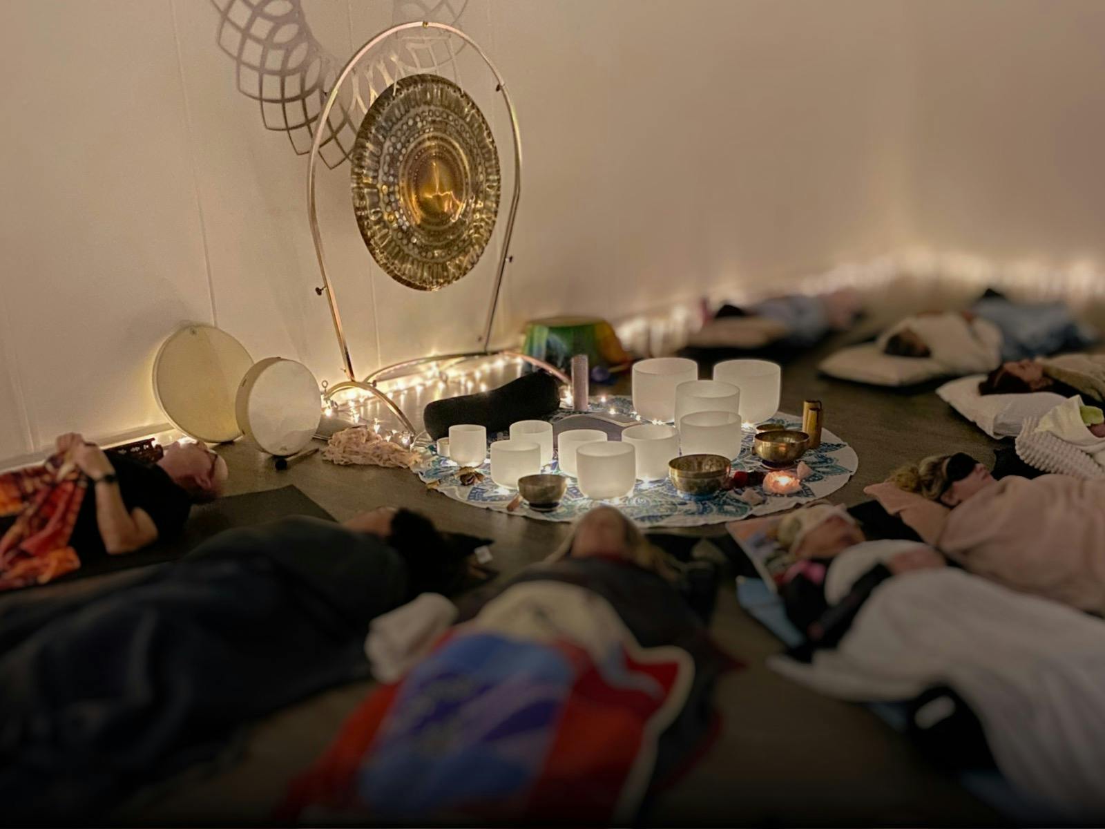Photo of sound bath guests with lying down sound bath instruments set up for the session.