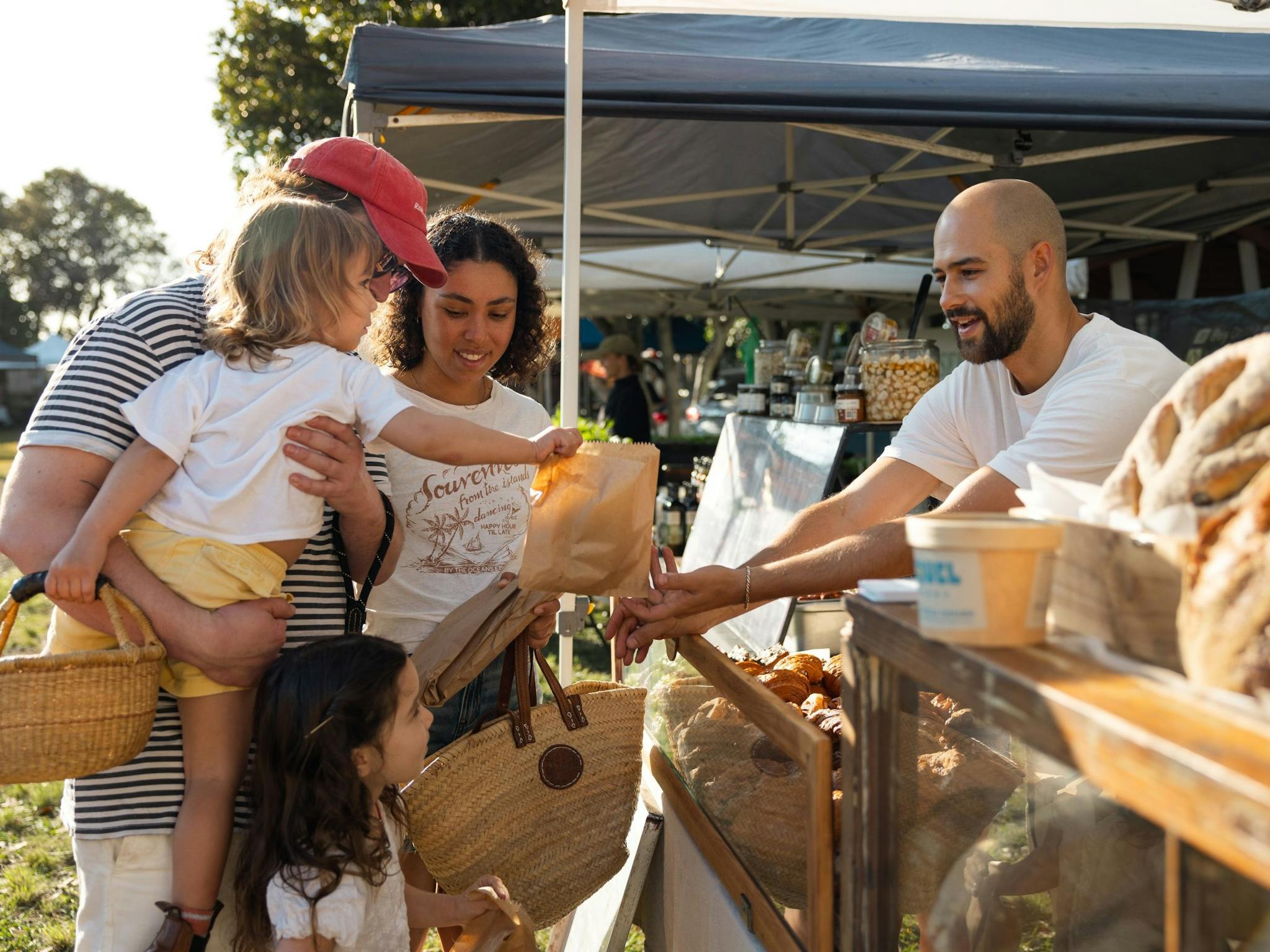 Image of a store holder offering baked goods to a family of four
