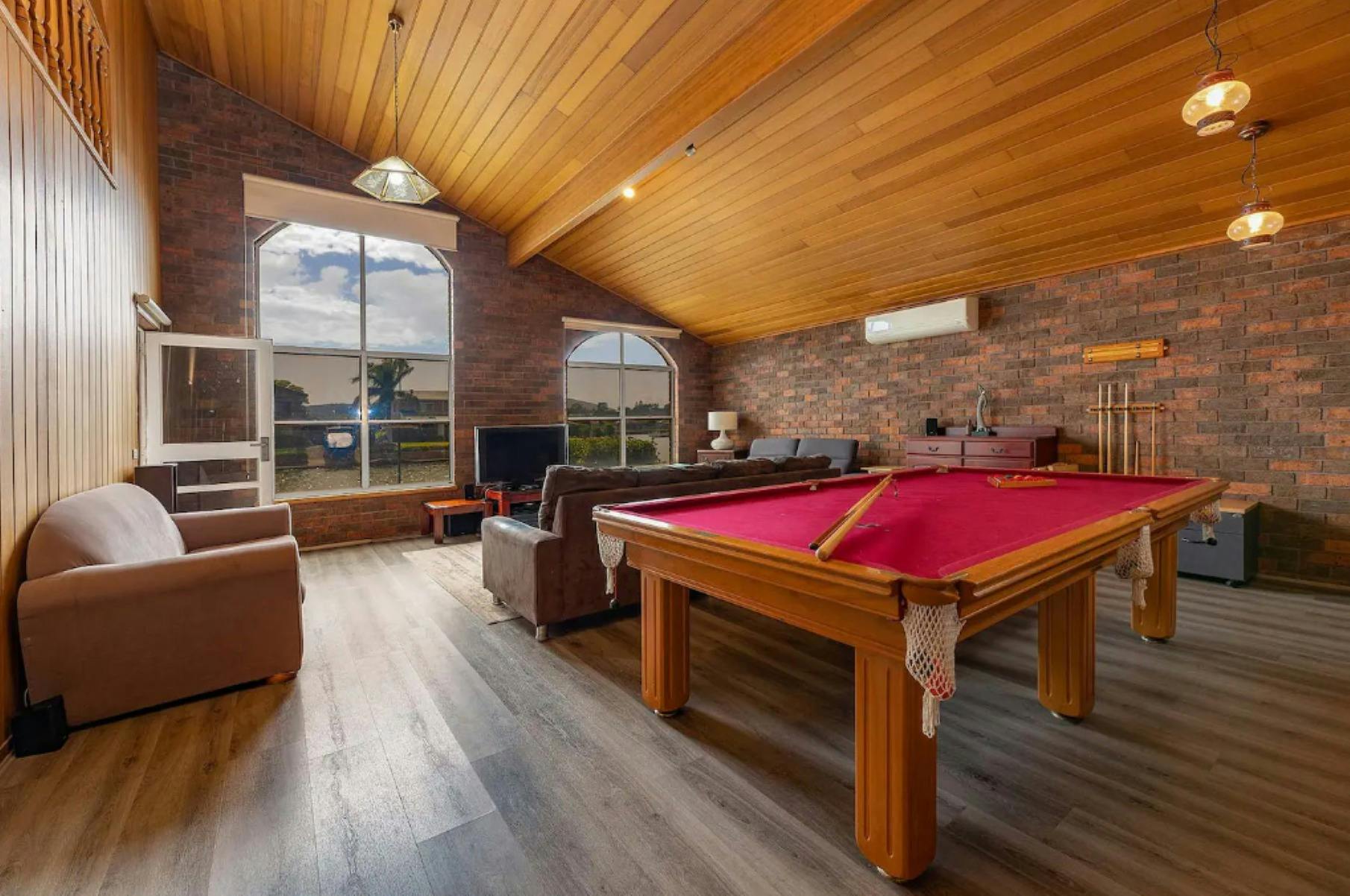 Rumpus room with high ceilings, pendant lights, pool table, lounges and TV
