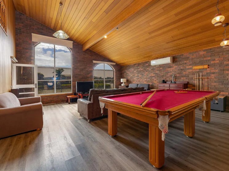 Rumpus room with high ceilings, pendant lights, pool table, lounges and TV