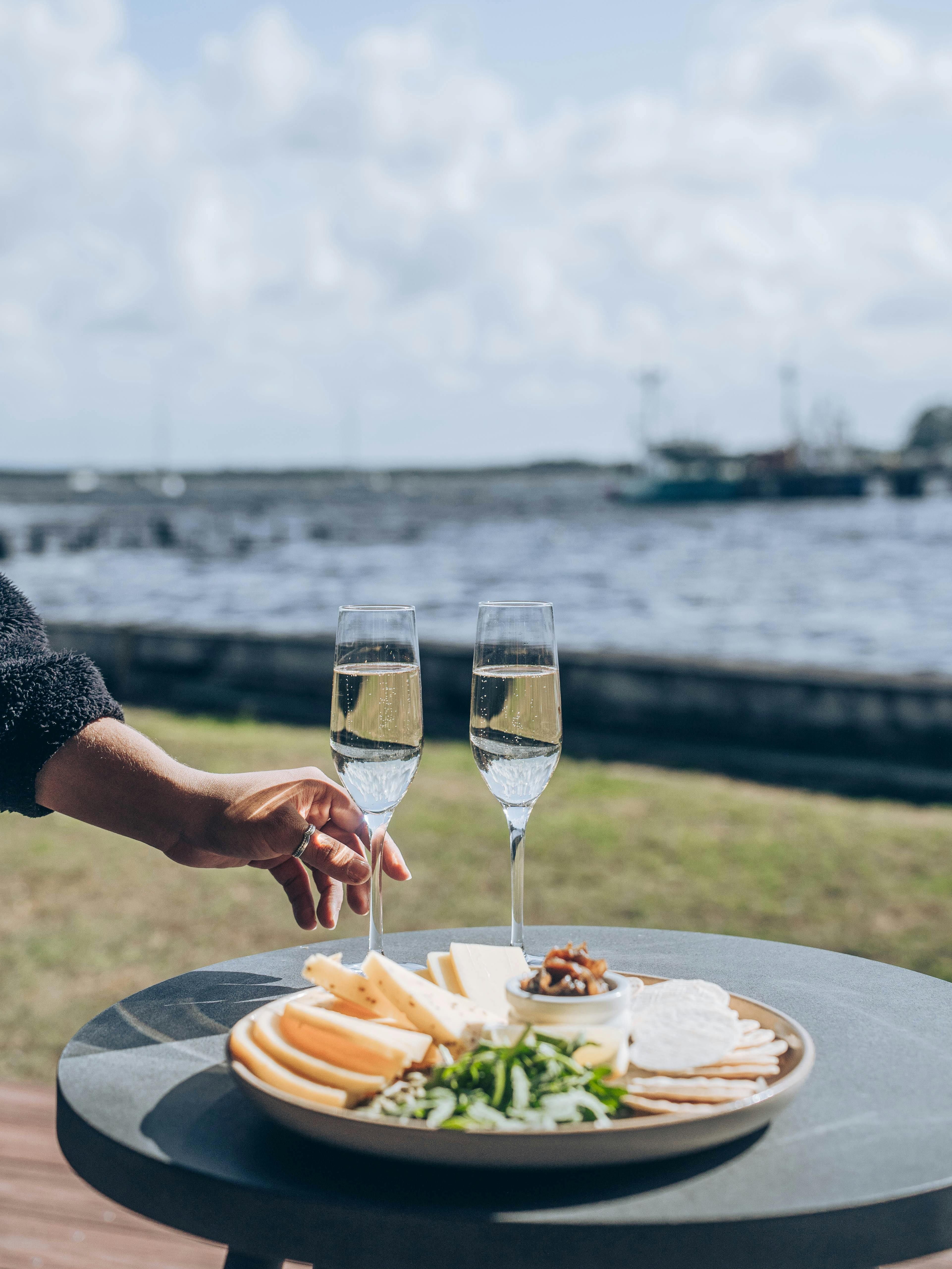 Wine and cheese plater with waterfront in the background