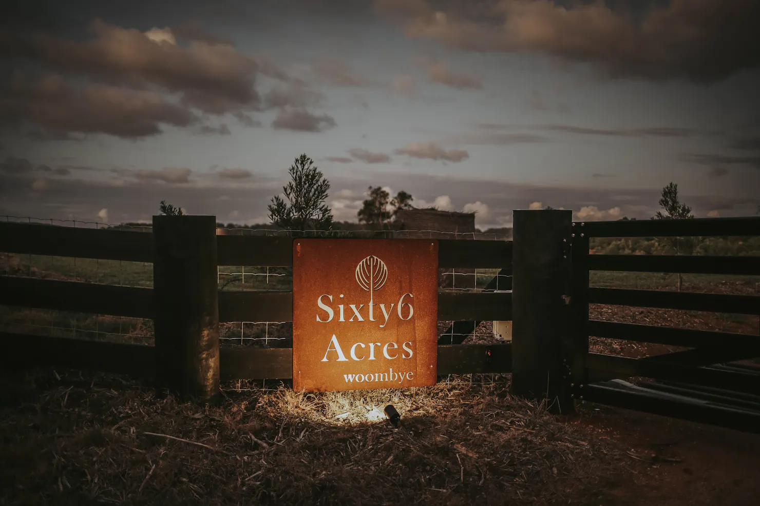 Sixty6 Acres entry sign at the front gate at dusk