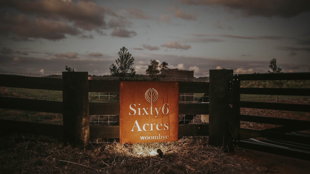 Sixty6 Acres entry sign at the front gate at dusk