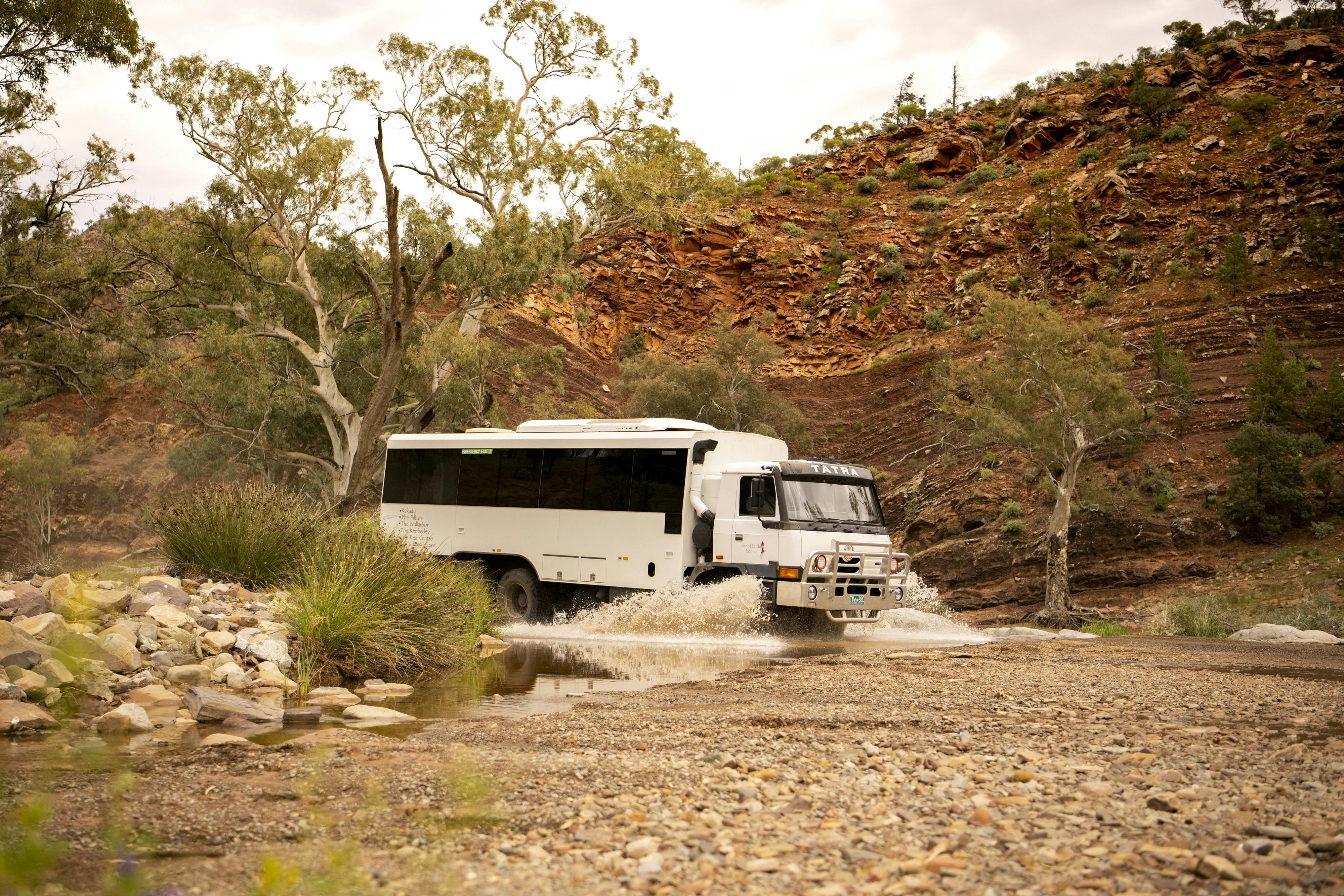 6WD coacj driving through a creek and riverbed