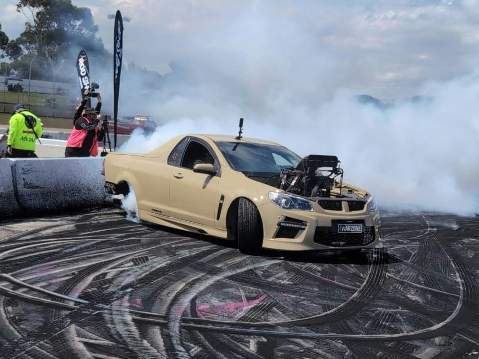 Cream supercharged burnout ute WARZONE producing heavy tyre smoke on the burnout pad.