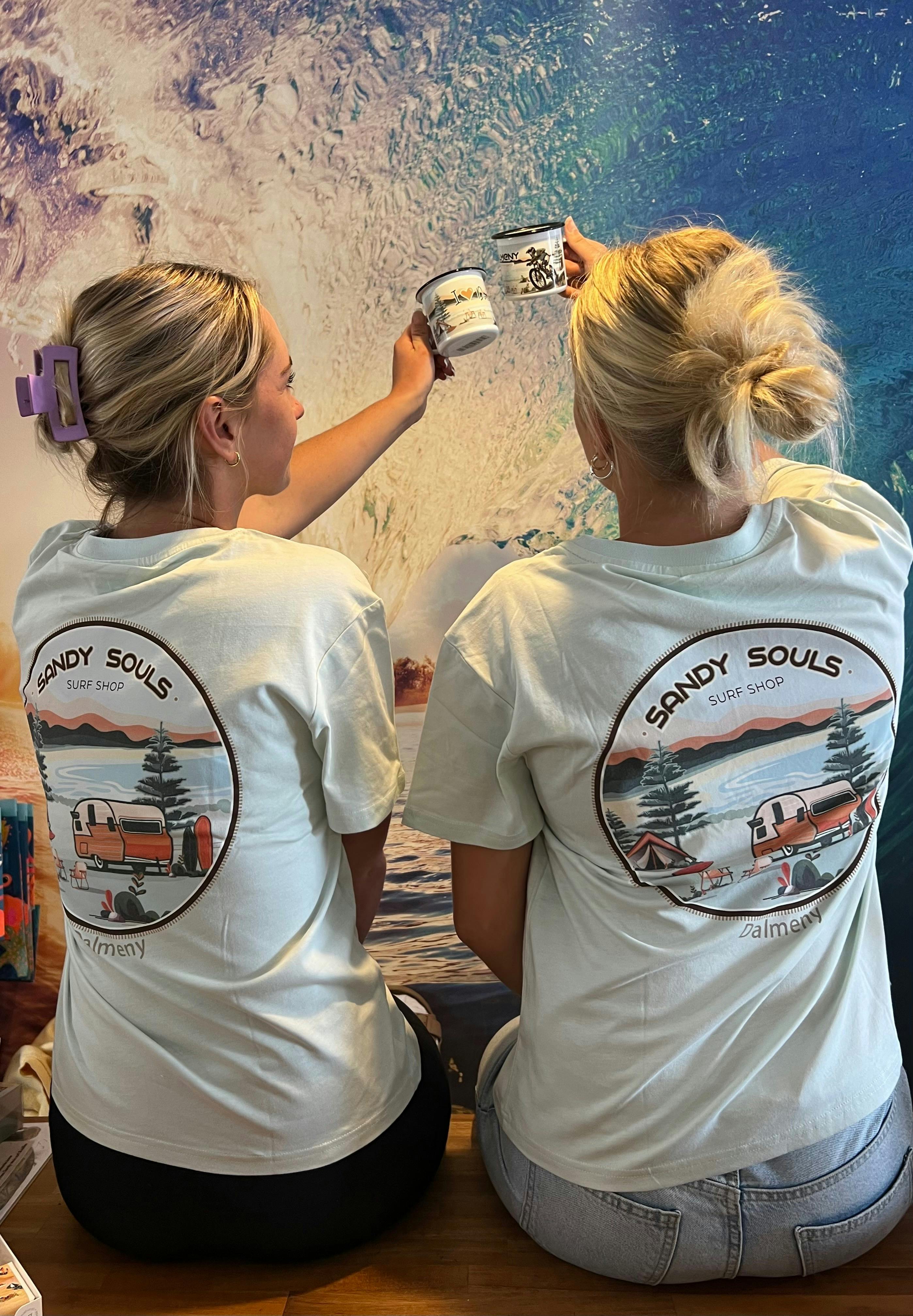 Two girls cheersing with takeaway coffee cups at Sandy Souls Surf and Coffee in Dalmeny, NSW