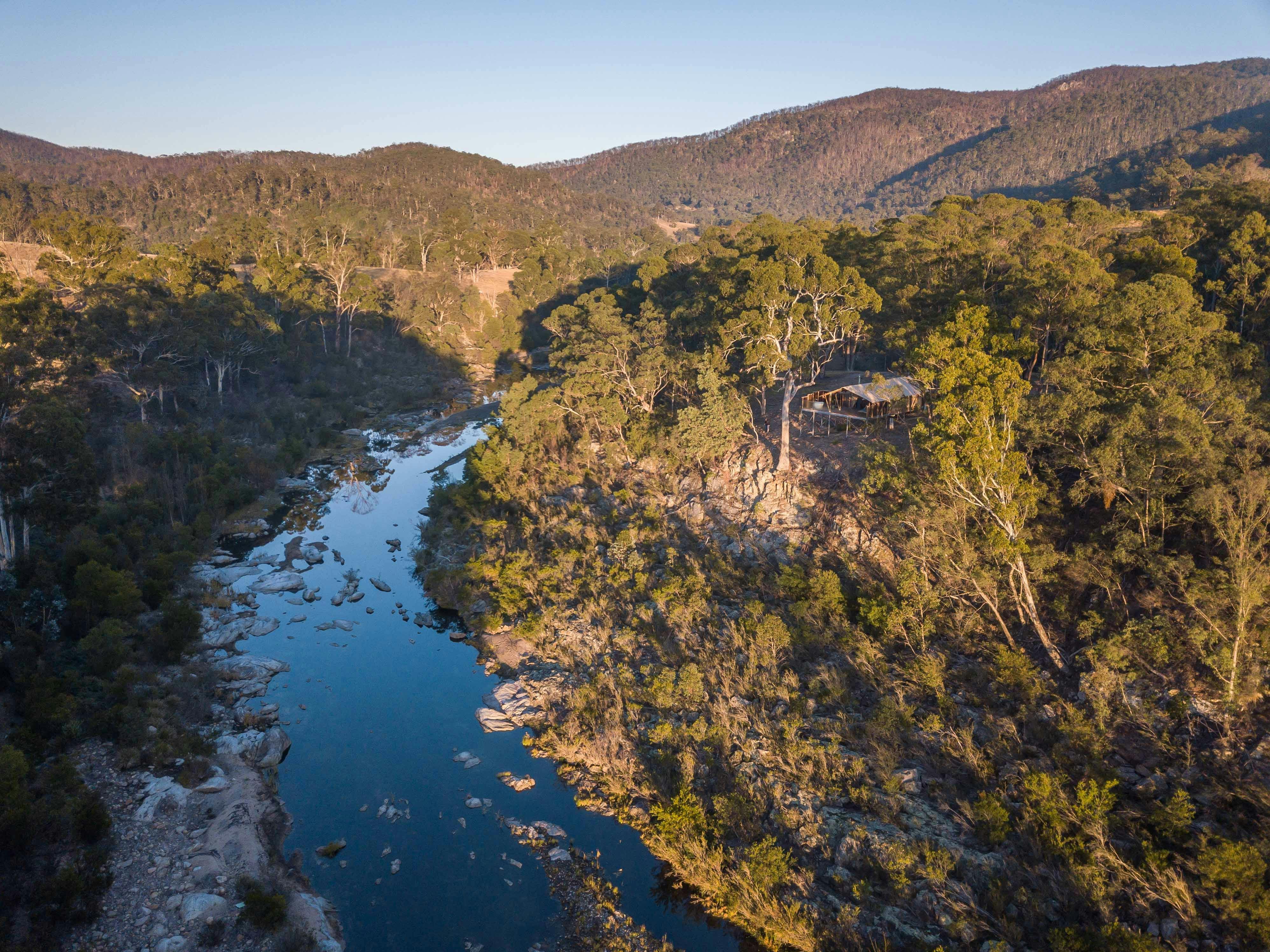 川を見下ろす木々に囲まれた崖の上に建つサファリテント