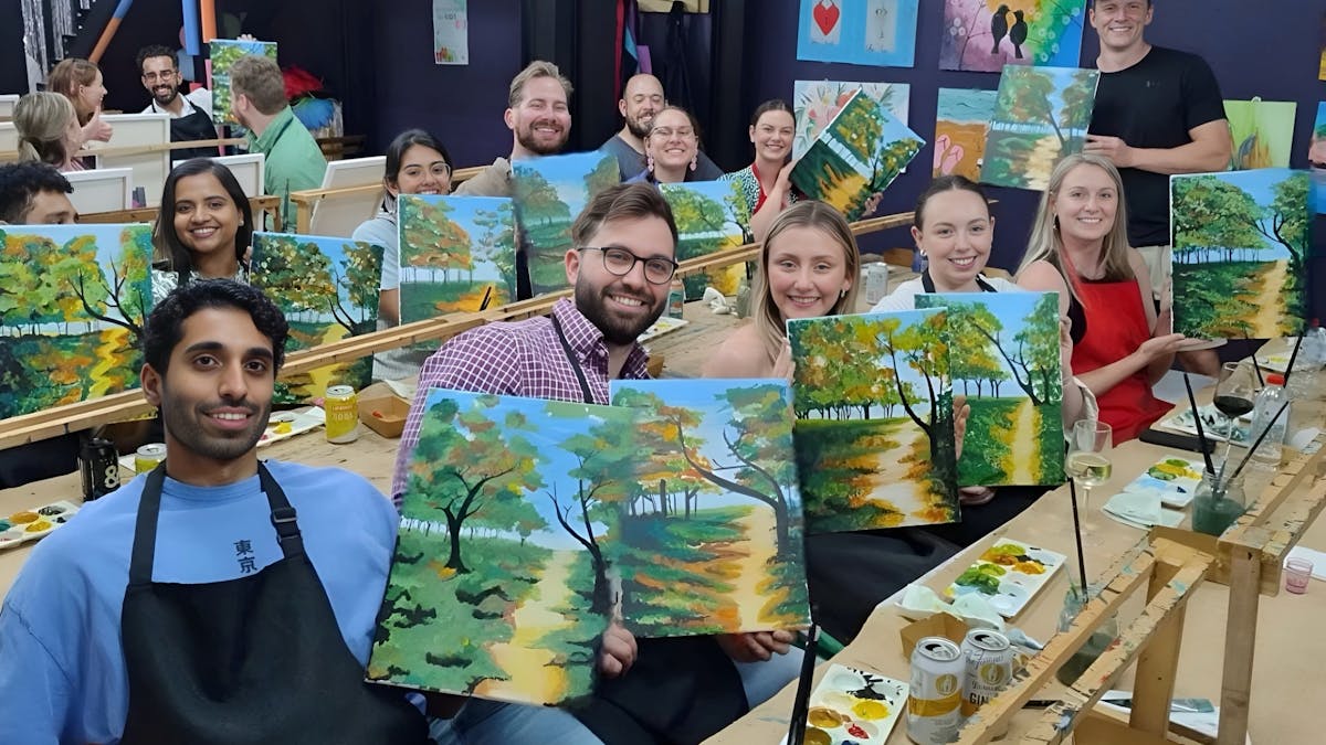 Artists proudly showing off their artwork of a beautiful beach scene.
