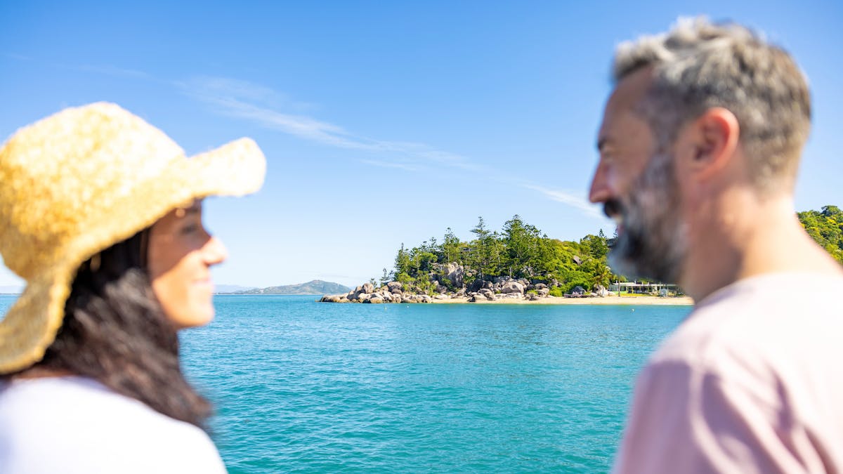 View across a bay with a couple in the foreground looking at each other, soft focus
