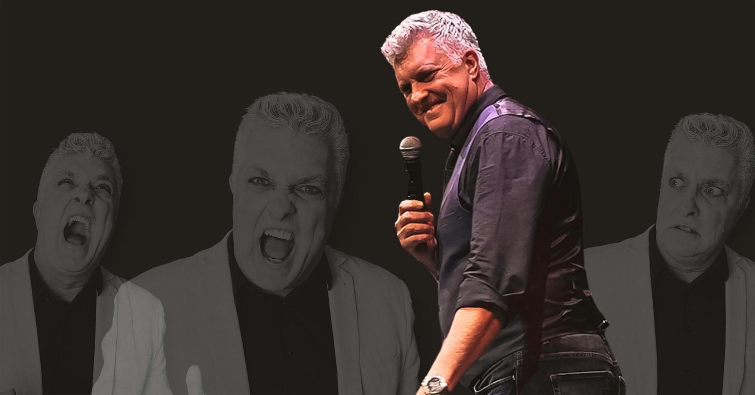 A man with grey hair looking behind his shoulder smiling with a microphone