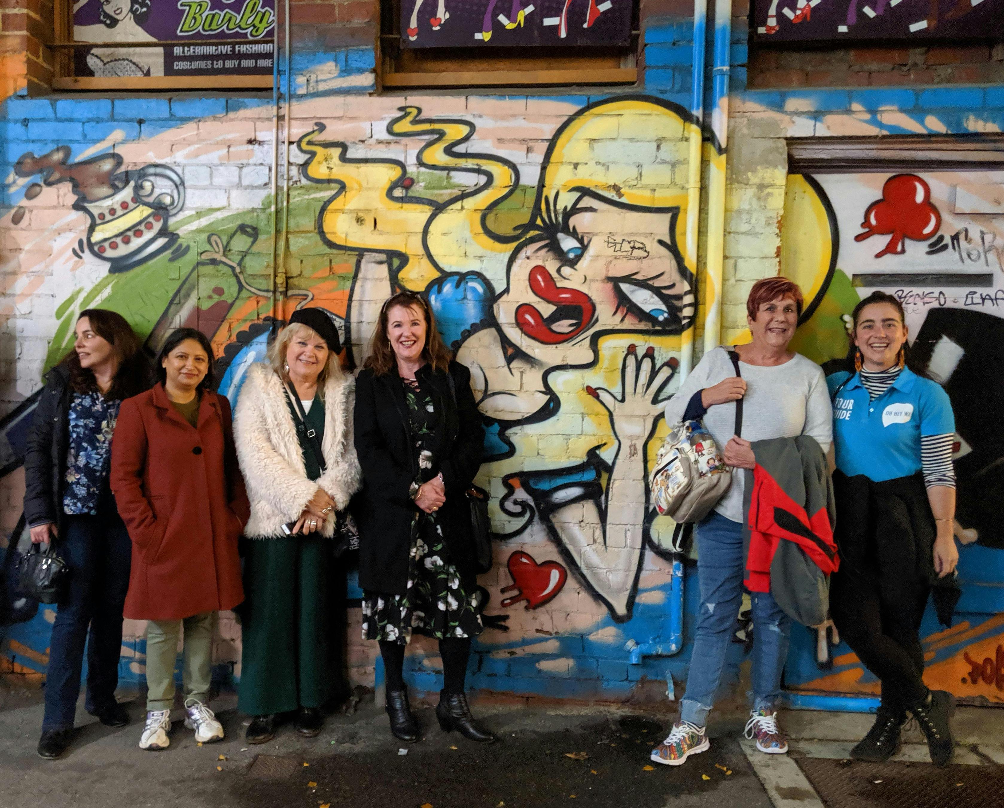 a tour group standing in front of a mural at night time