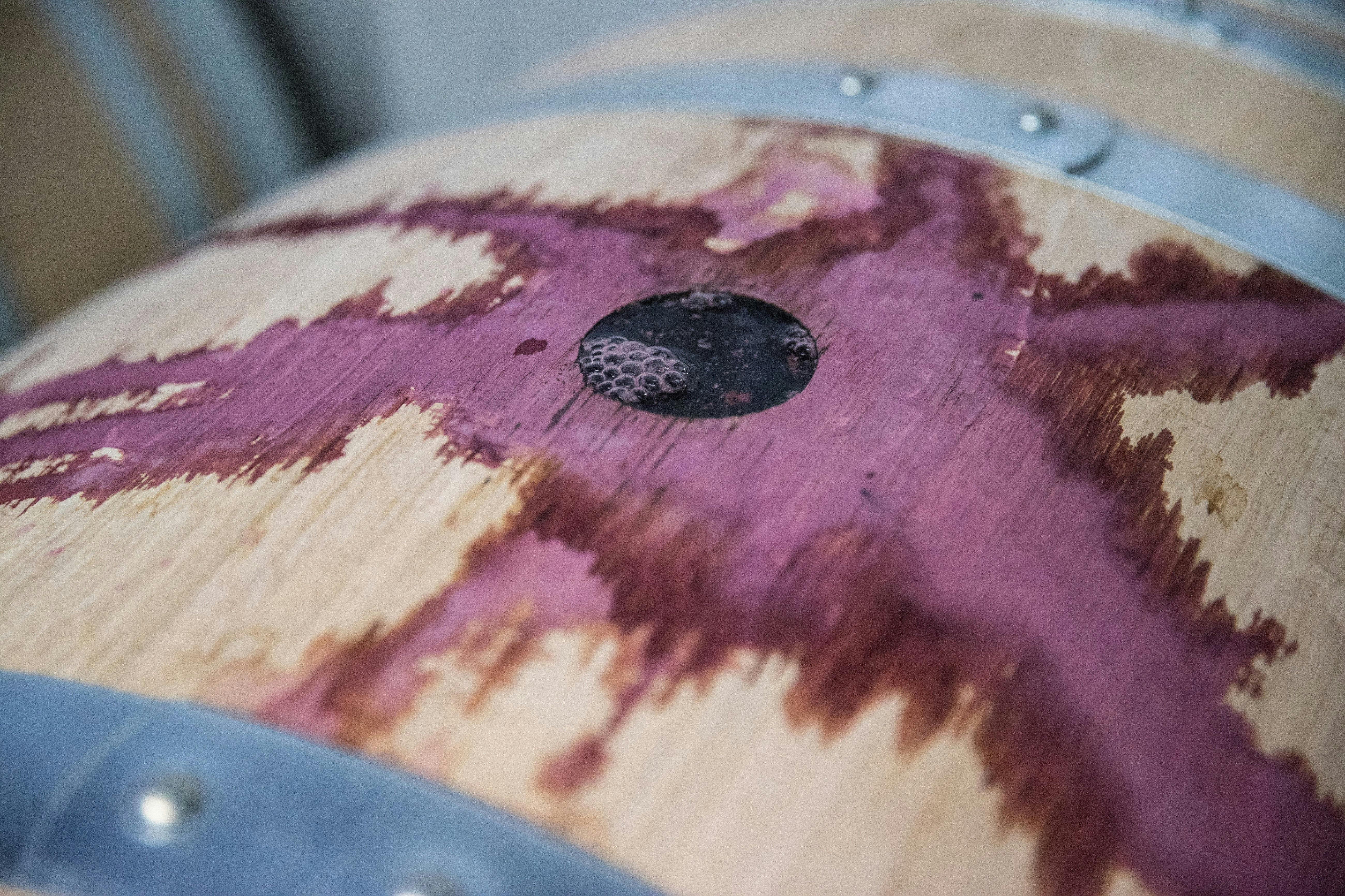 Red wine spills over the top of a French oak barrel.