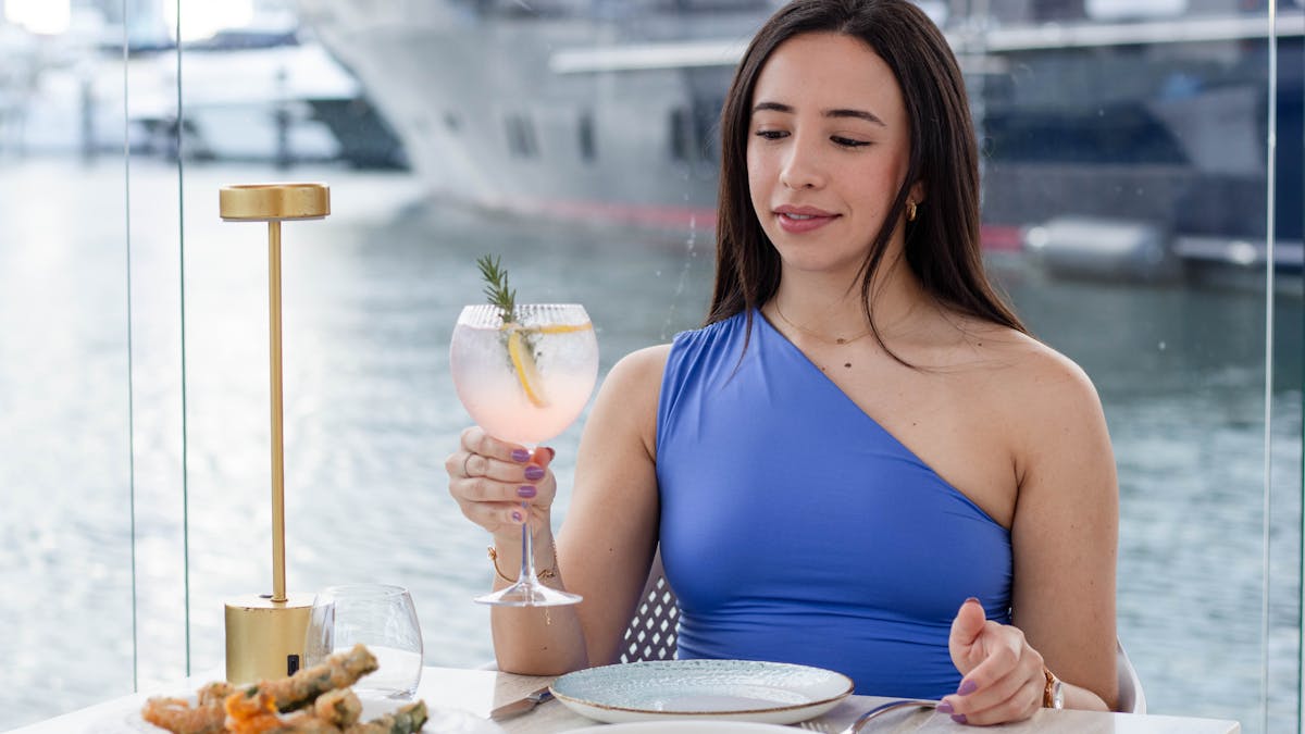 Diner enjoying a glass of wine at MĀRE overlooking the marina