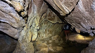A cave with a hiker walking through.