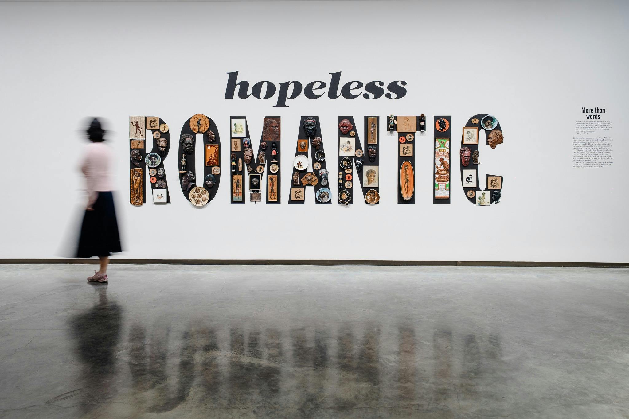 Hopeless romantic on a white wall. Romantic is spelled using objects of Aboriginalia as the letters