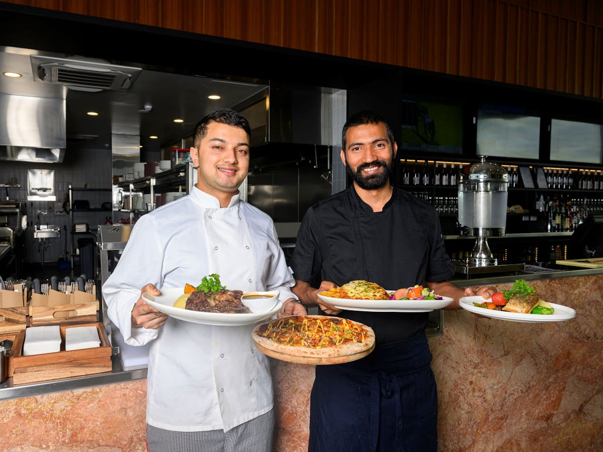 Two chefs holding plated meals Two chefs holding plated meals
